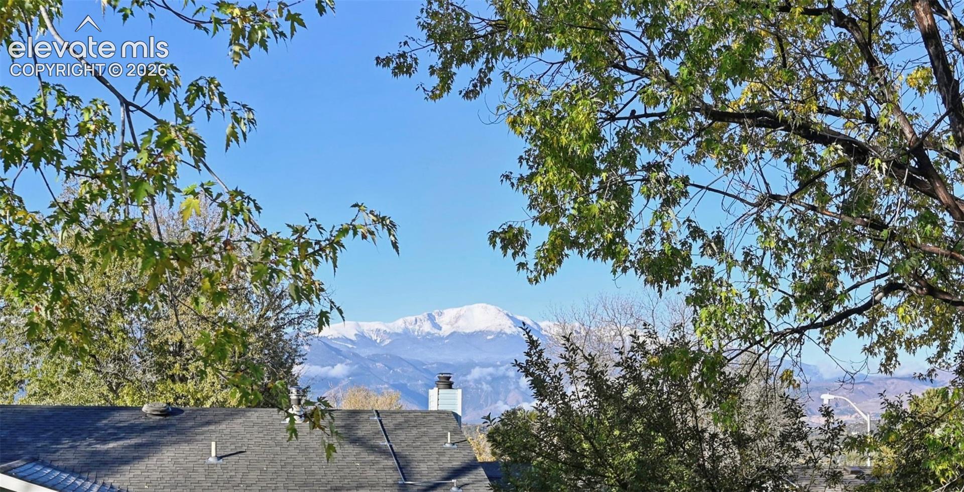 Amazing view of Pikes Peak right from the deck with Snow-capped mountain backdrop framed by mature deciduous trees