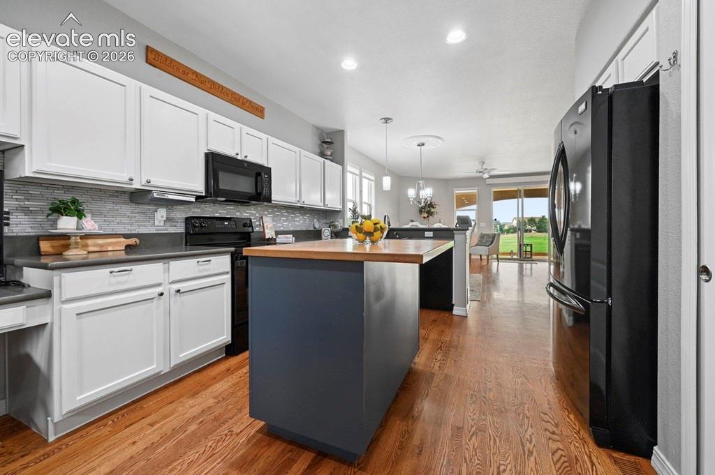 Kitchen featuring white cabinetry, a tiled backsplash, and wood-finish flooring