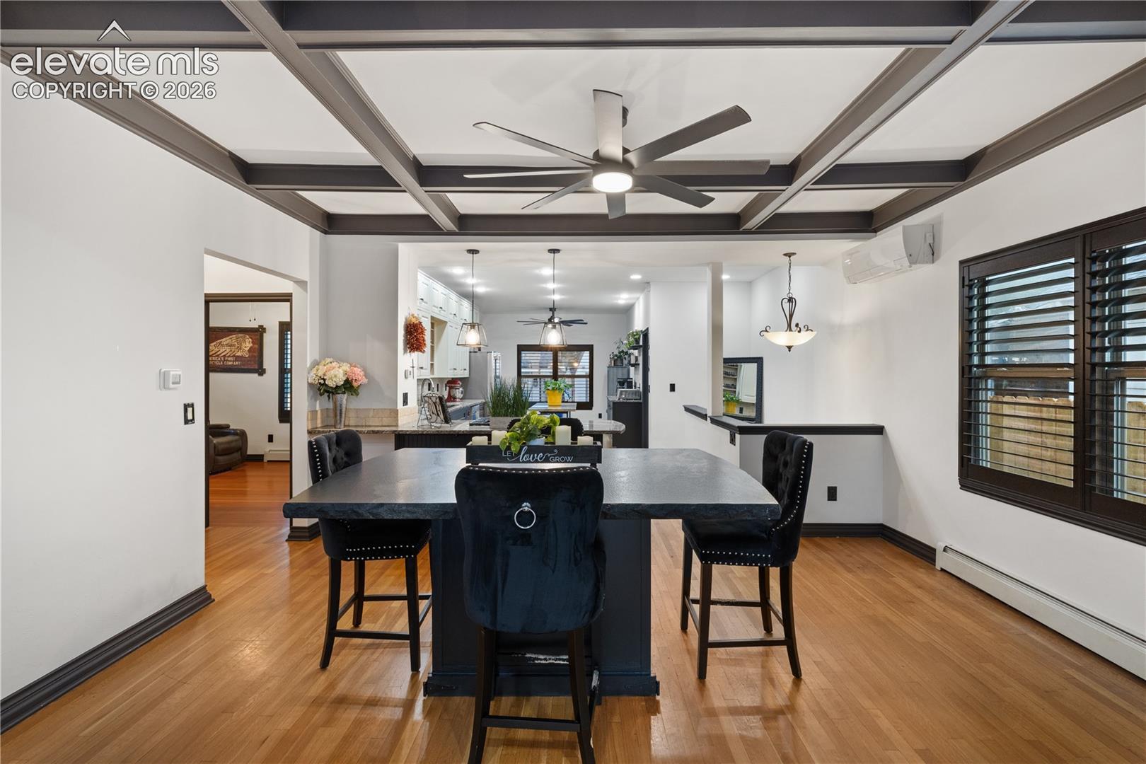 Coffered ceiling with integrated ceiling fan, hardwood flooring, and custom window shutters