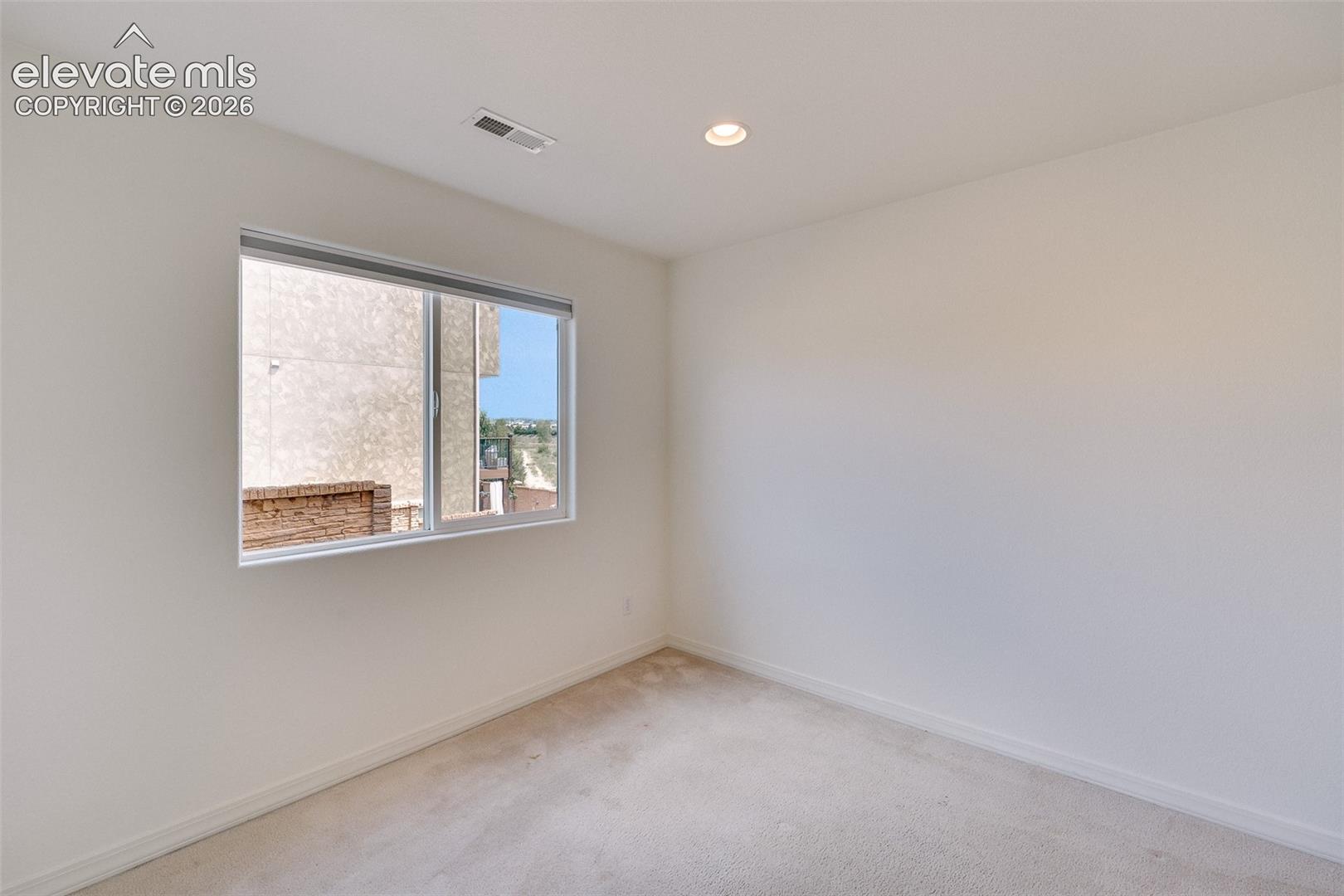 Recessed ceiling lighting, white walls, and light-toned carpeting