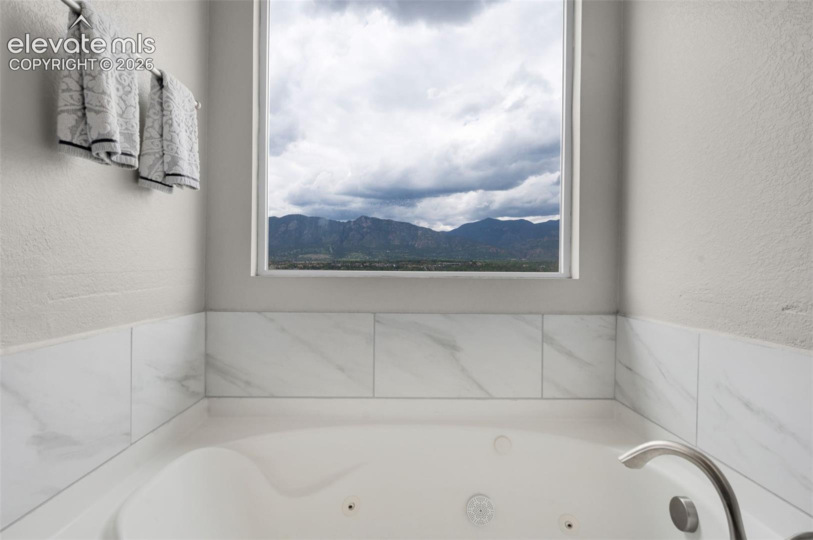 Built-in jetted tub with a mountain view, tile surround, and brushed metal fixtures