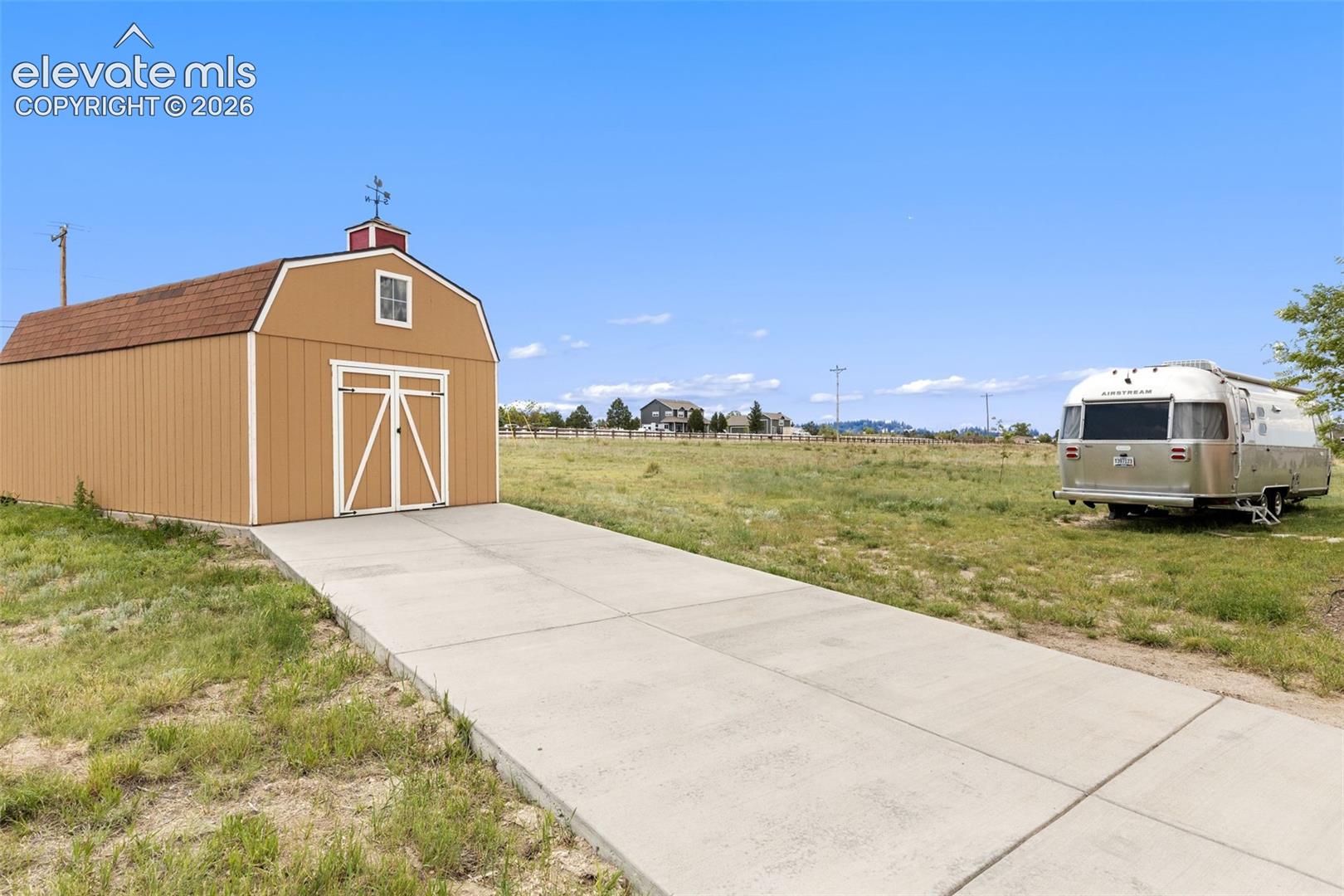 Shed on concrete pad at end of driveway provides extra storage