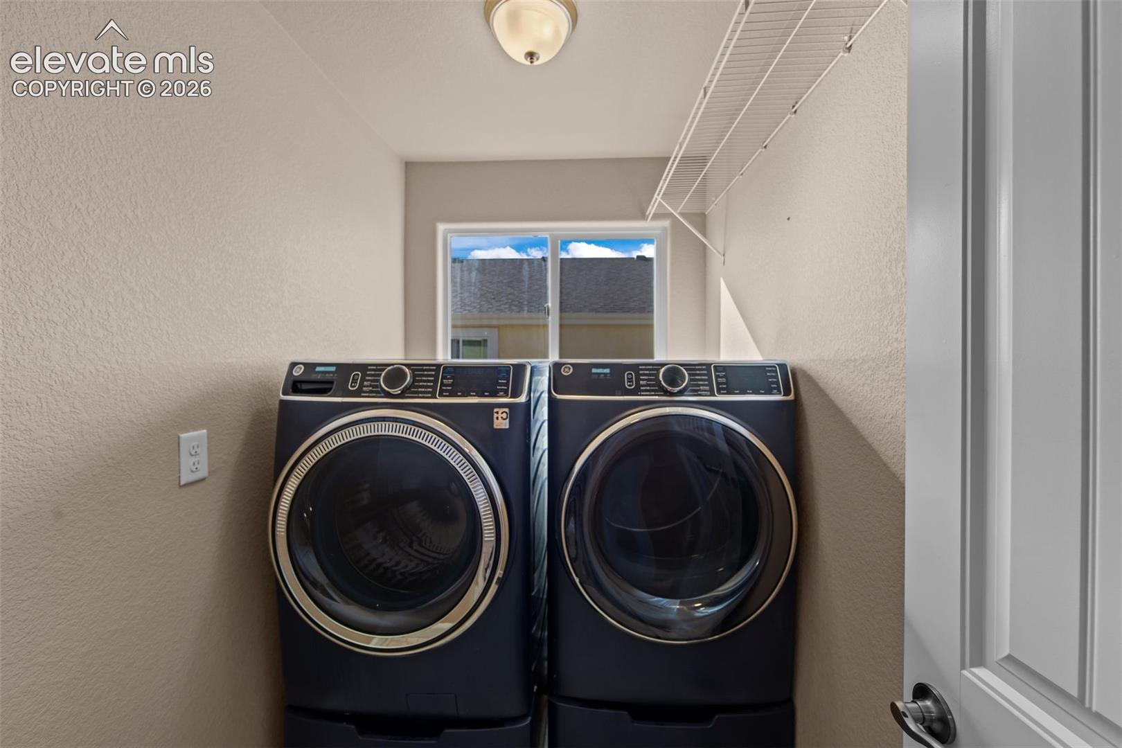 Laundry area featuring a window, built-in wire shelving, and a flush-mount ceiling light fixture
