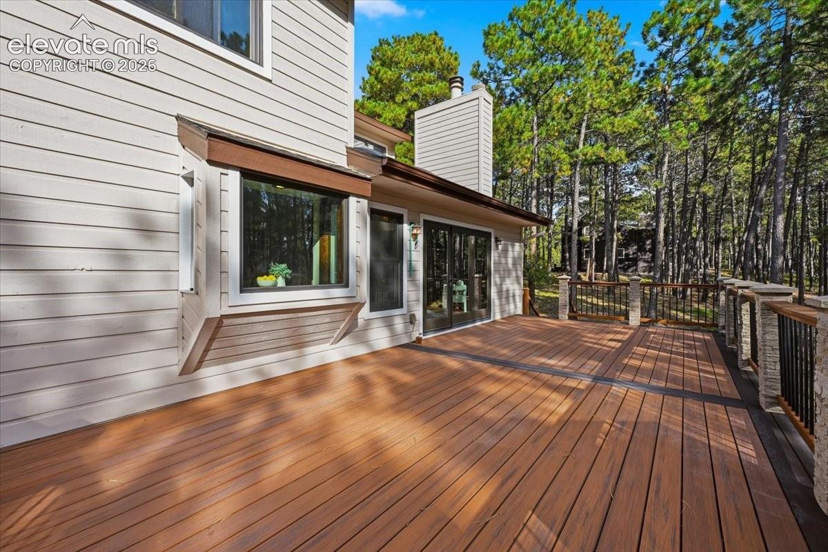 Expansive multi-level deck, wood-finish flooring, stone pillars, wrought iron railing, and large bay window