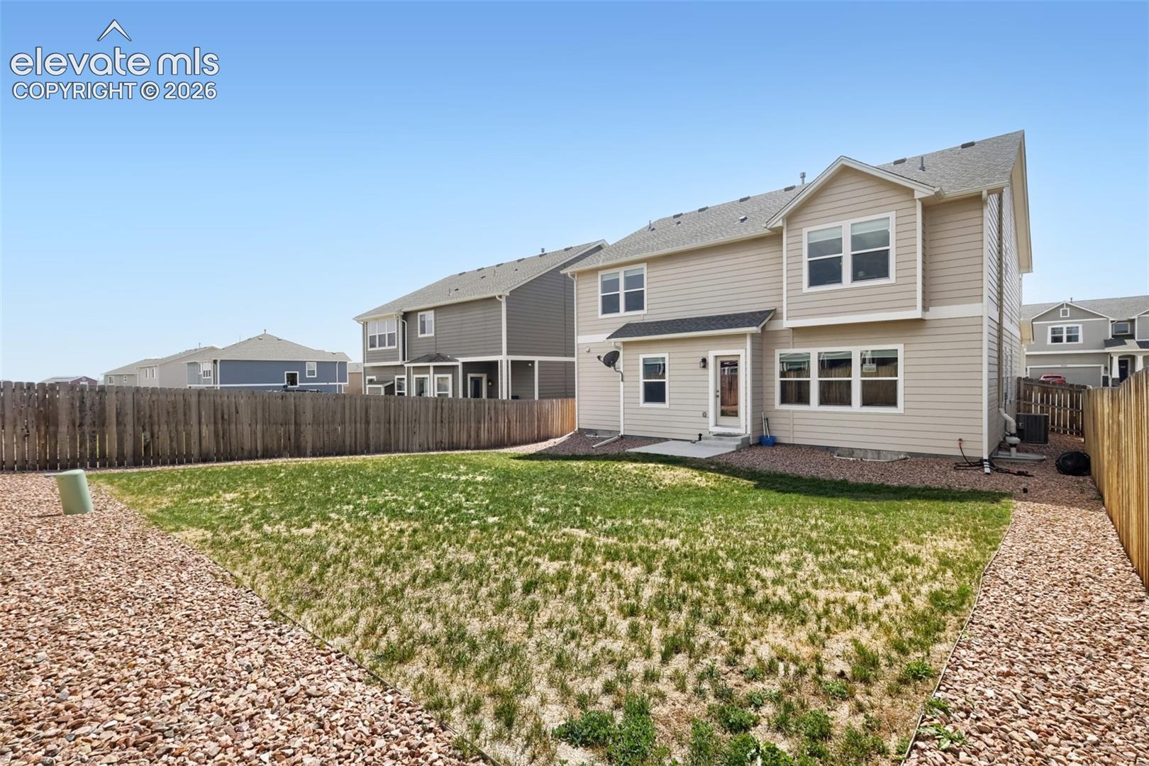 Expansive backyard featuring a wood fence, gravel landscaping, and a concrete patio
