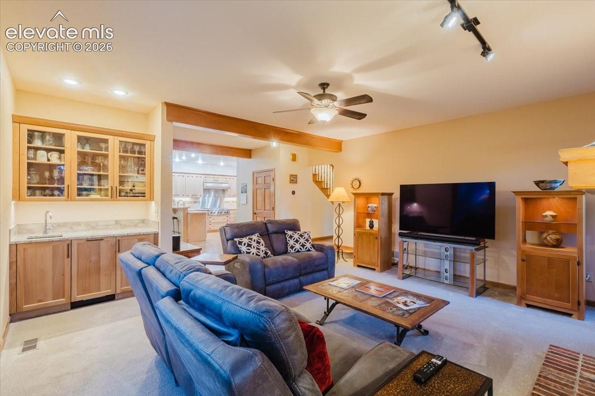 Open-concept living area featuring a wet bar with glass-front cabinetry and a sink