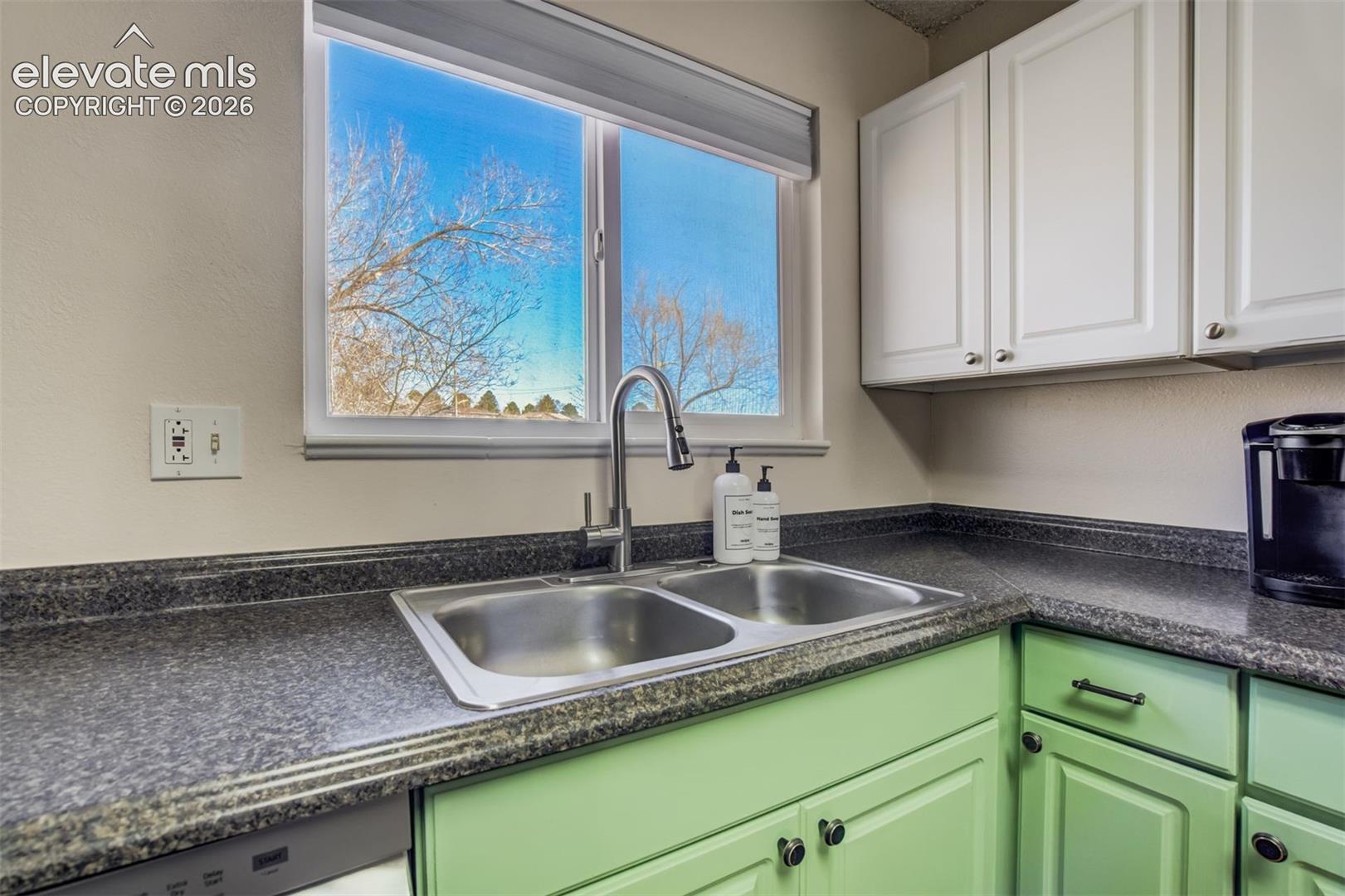 Kitchen area featuring a window above a stainless steel double-basin sink with a pull-down faucet
