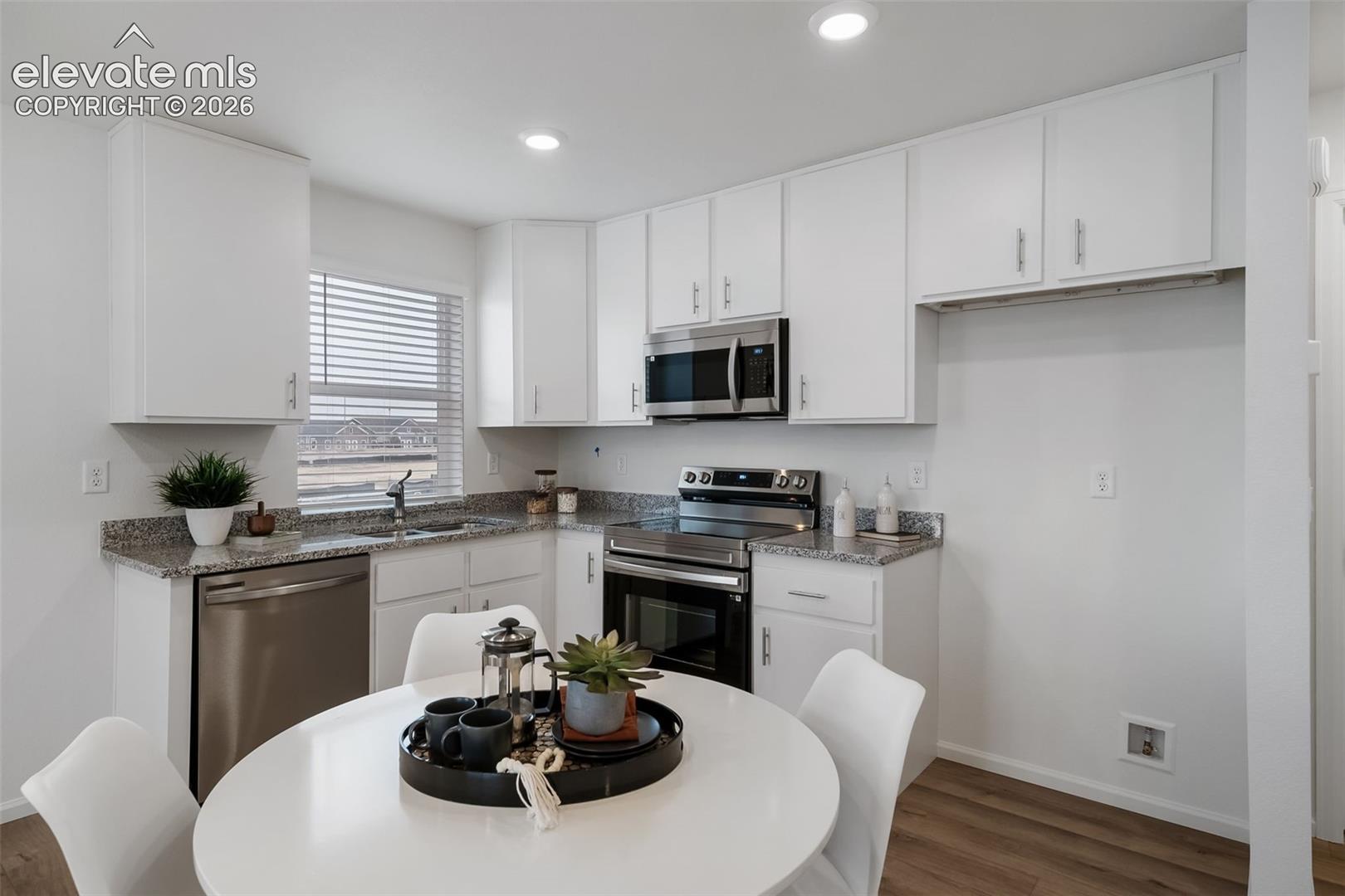 Well-appointed kitchen featuring white cabinetry, stainless steel appliances, granite-style countertops, recessed lighting, and wood-finish flooring
*photos of a model home*