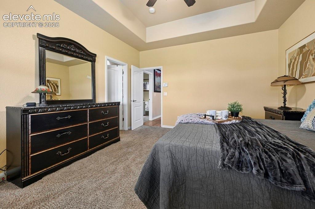 Recessed ceiling with a ceiling fan, light beige wall color, and light-toned carpeting