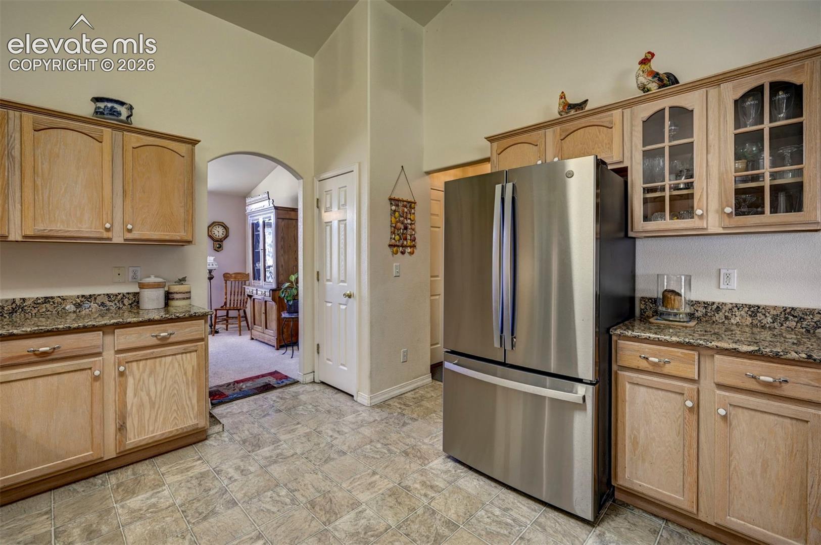 Kitchen area with wood finish cabinets some with glass doors, granite countertops and stainless steel appliances.