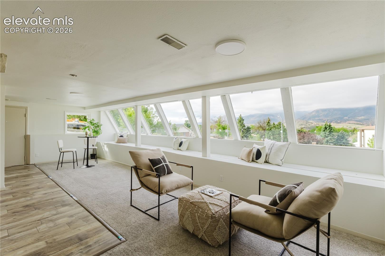 Bright room featuring panoramic windows, a built-in window bench, wood-finish flooring, and light-toned carpeting