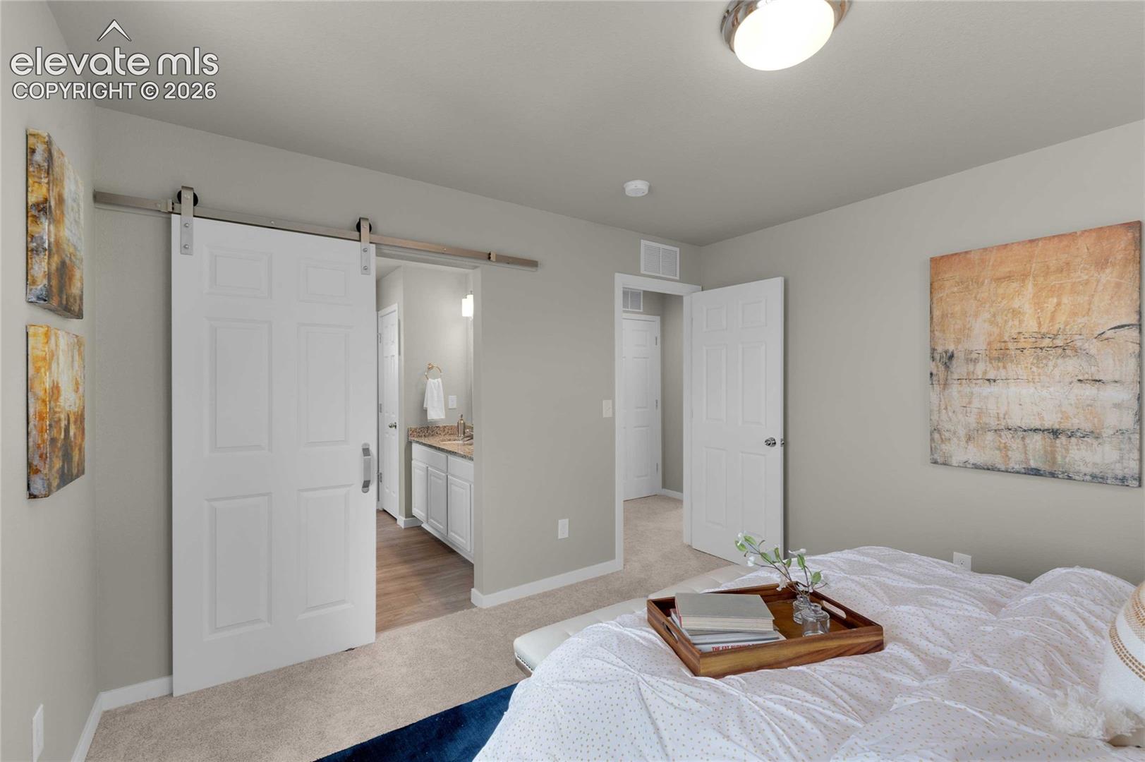 White paneled barn door on a stainless steel track, light gray painted walls, and light-colored carpet flooring
*photos of a model home*