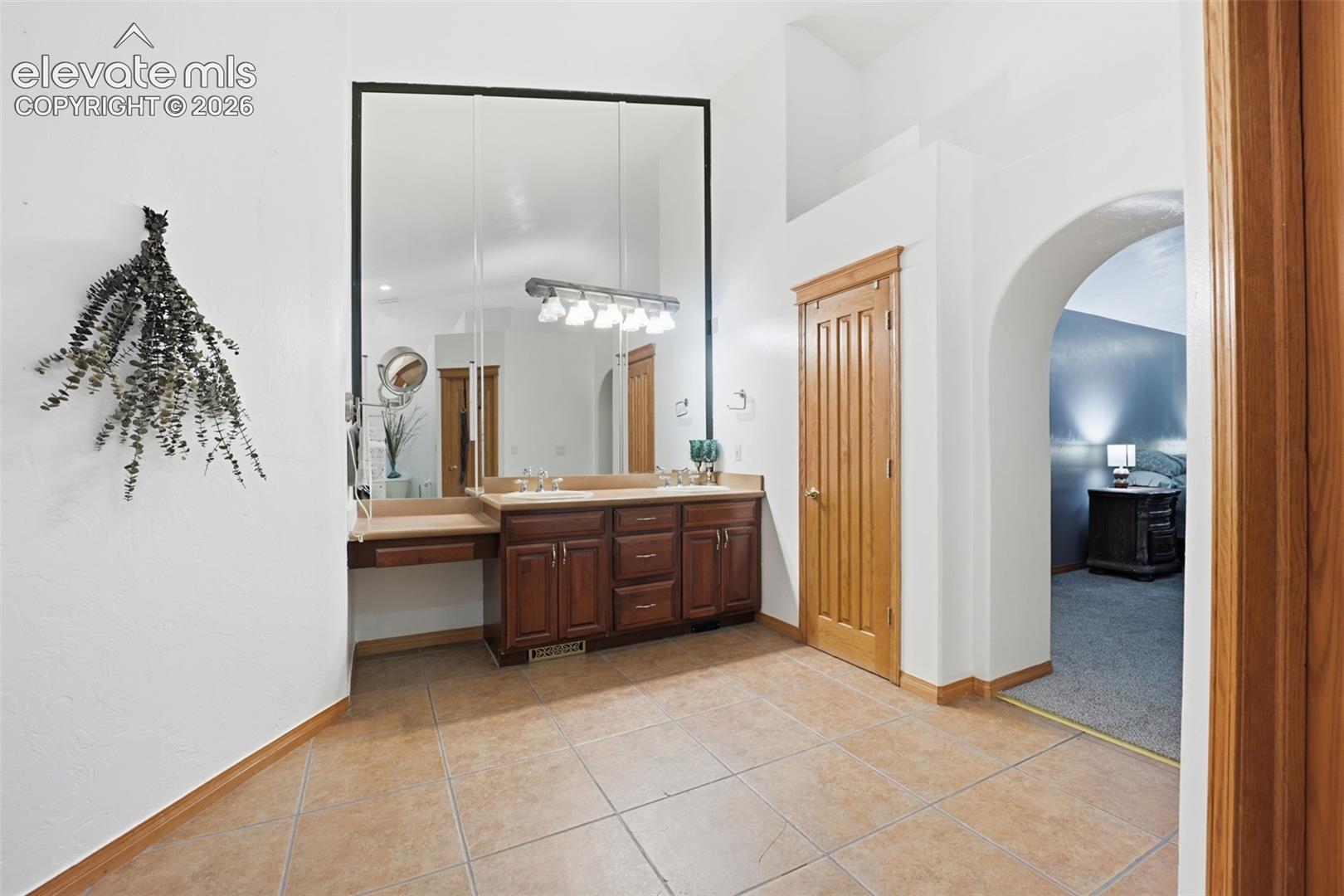 Double vanity with integrated makeup counter, multiple mirrors, and tile flooring