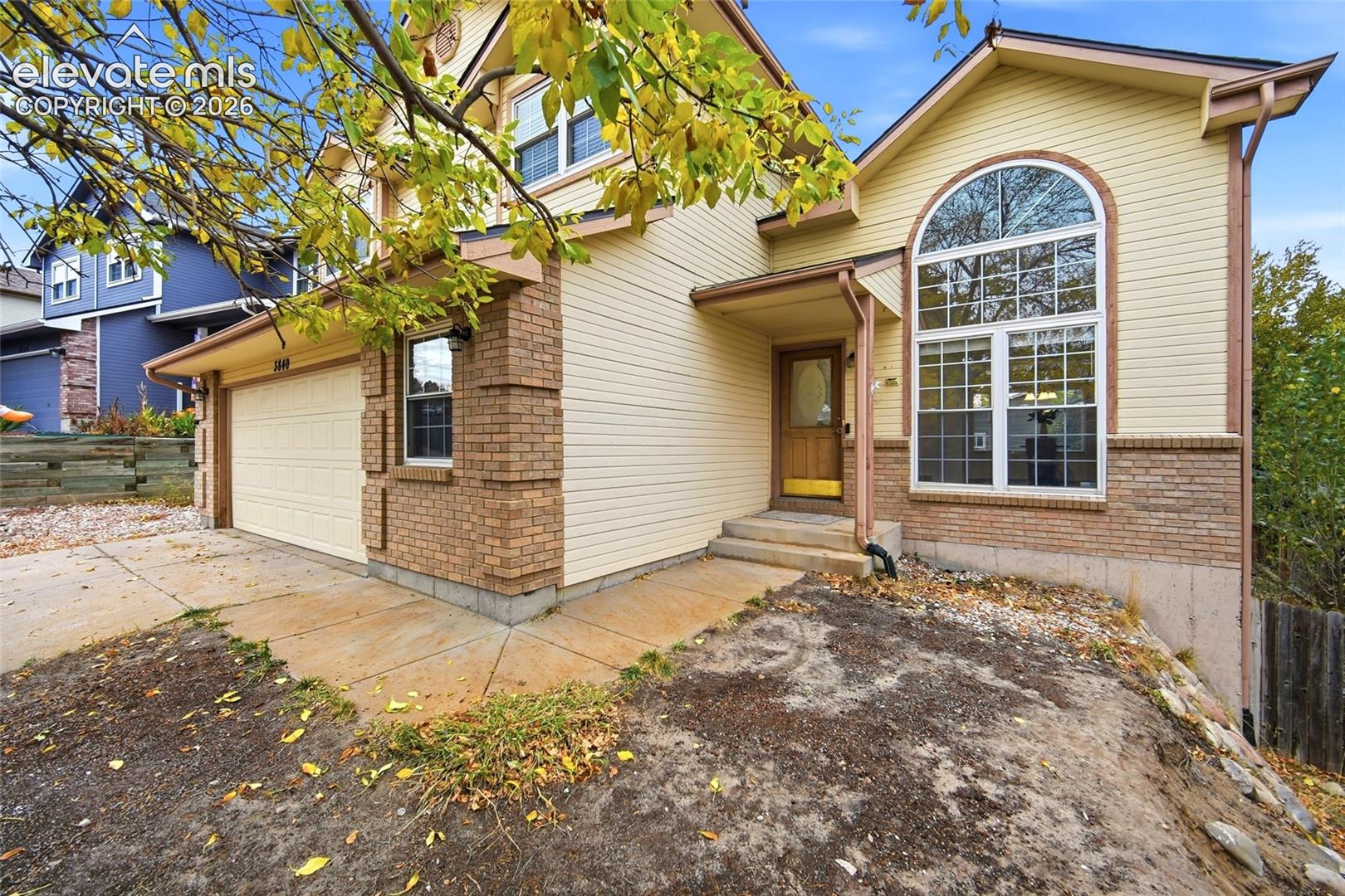 Multi-level exterior featuring horizontal siding, brick masonry detailing, an arched window, a covered entryway, and an attached two-car garage