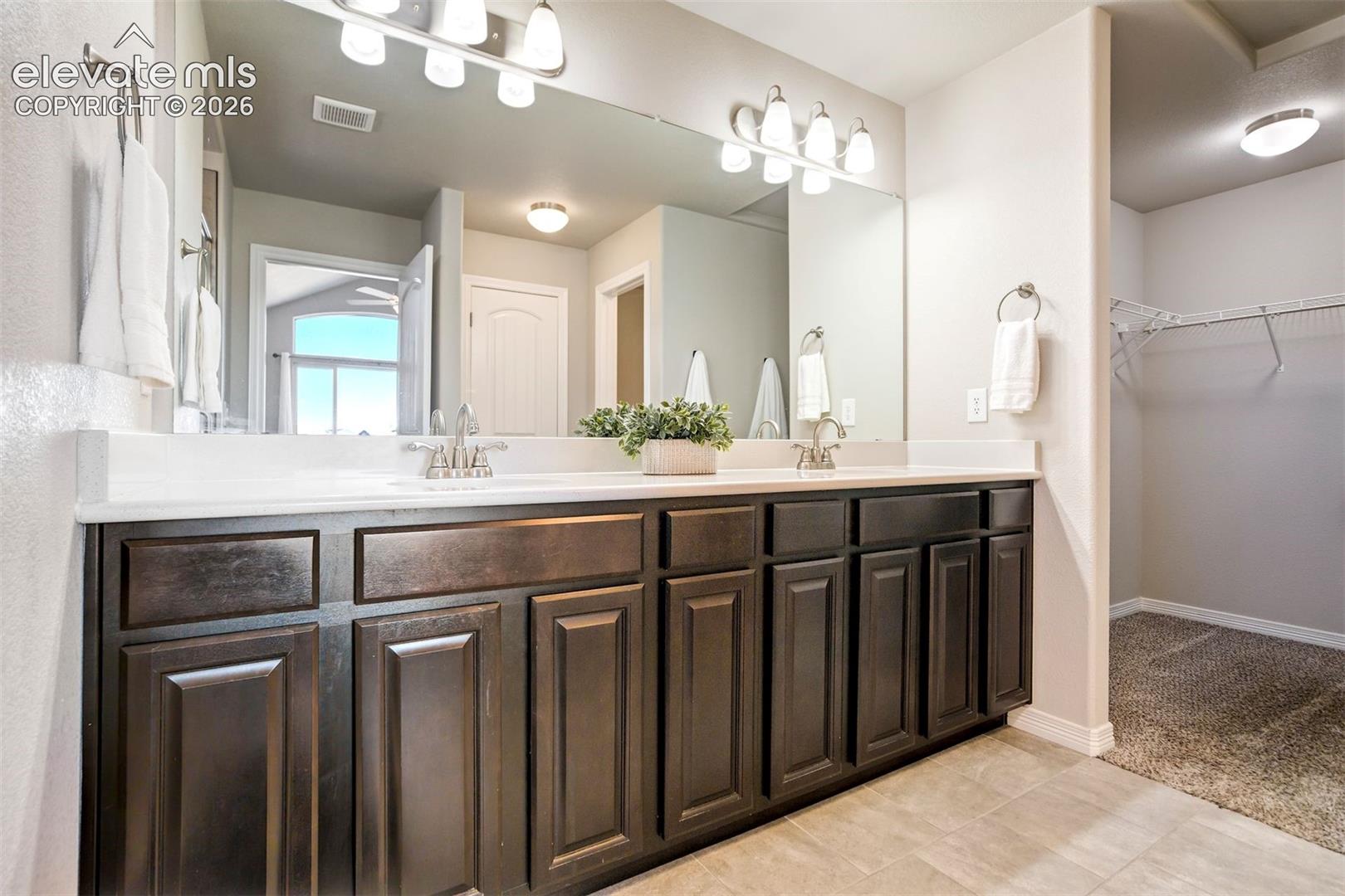 Dual vanity with dark wood-finish cabinetry, integrated sinks, and polished chrome faucets