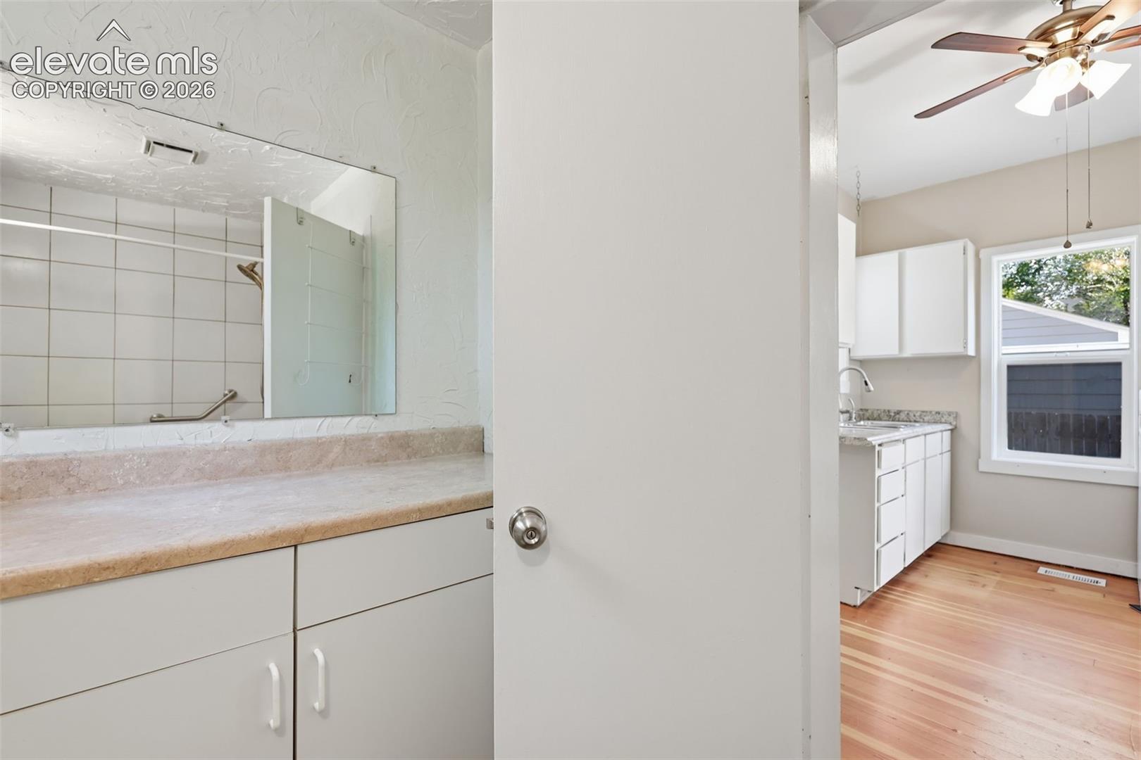 Bathroom vanity with white cabinetry, a built-in mirror, and light-toned countertops