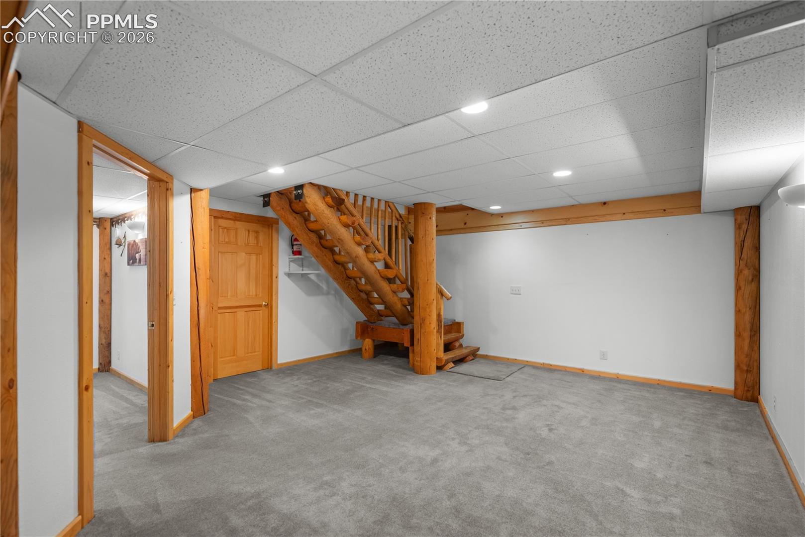 Finished basement with carpet, stairs, recessed lighting, and a paneled ceiling