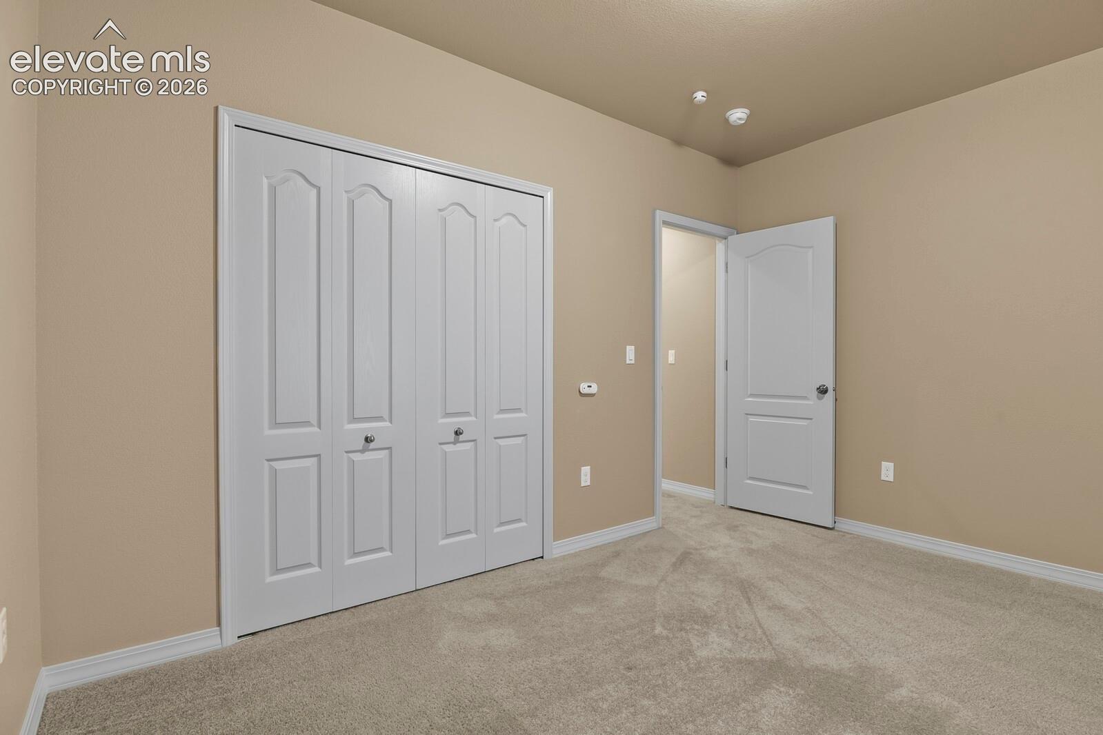 Plush carpet flooring, neutral wall tones, white bi-fold closet doors, and white interior doors