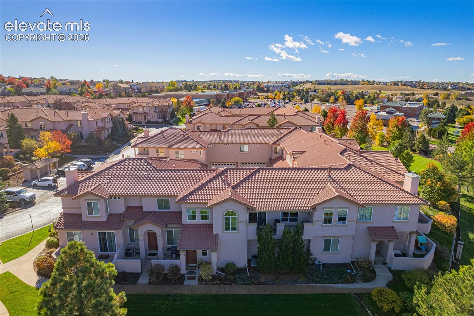 Multi-unit residential complex featuring a tile roof, stucco exterior, integrated garage structures, and dedicated pedestrian walkways