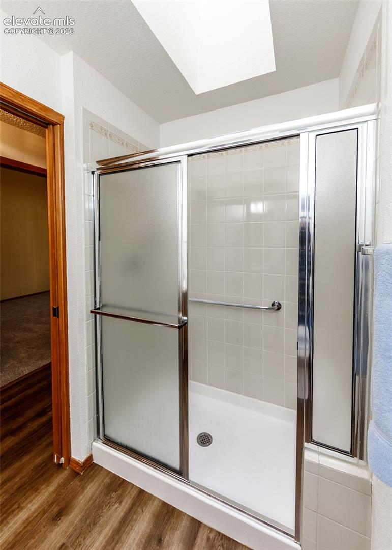 Shower with sliding frosted glass doors, white tile surround, and grab bar