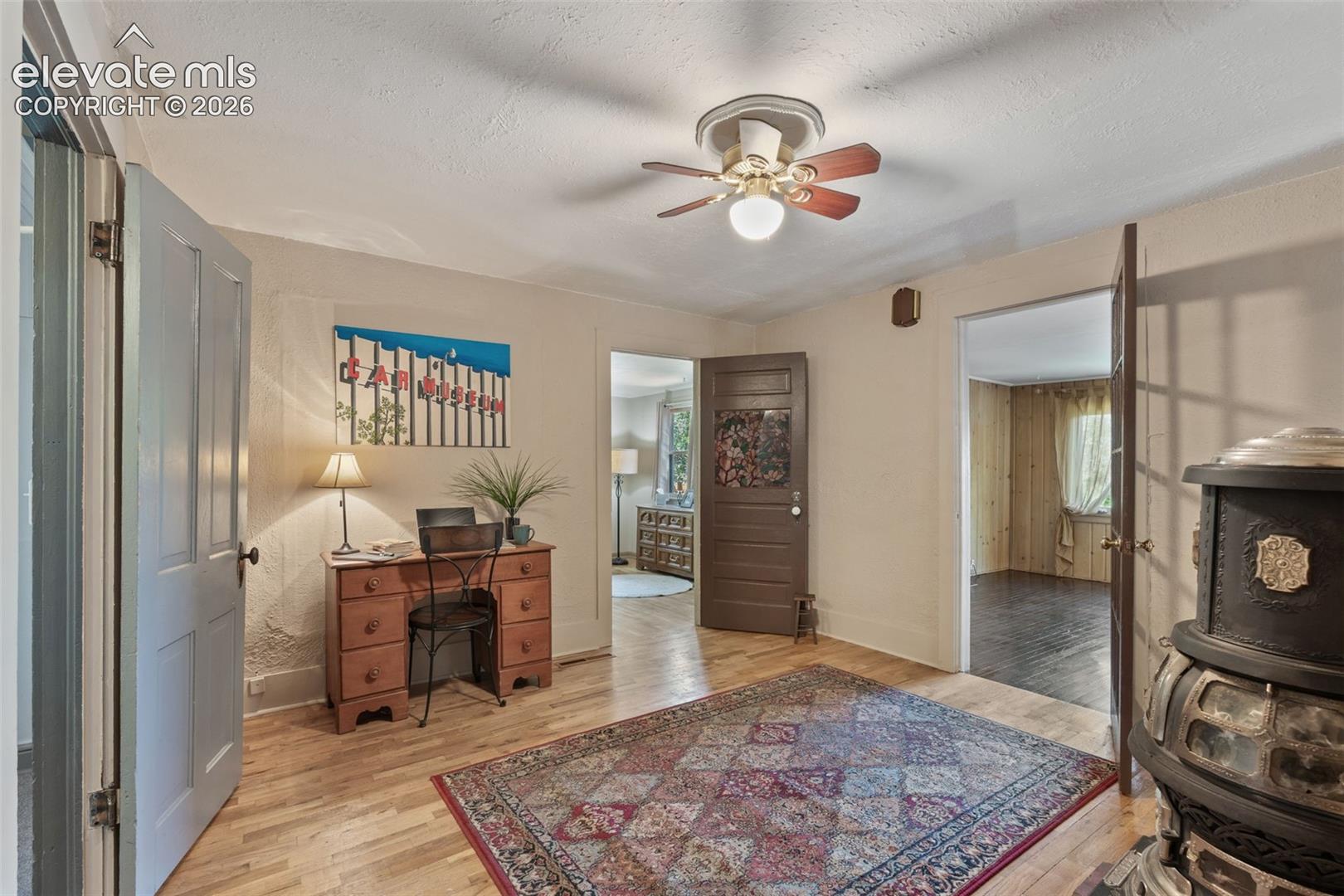 Room featuring light wood-finish flooring, a ceiling fan, and multiple doorways