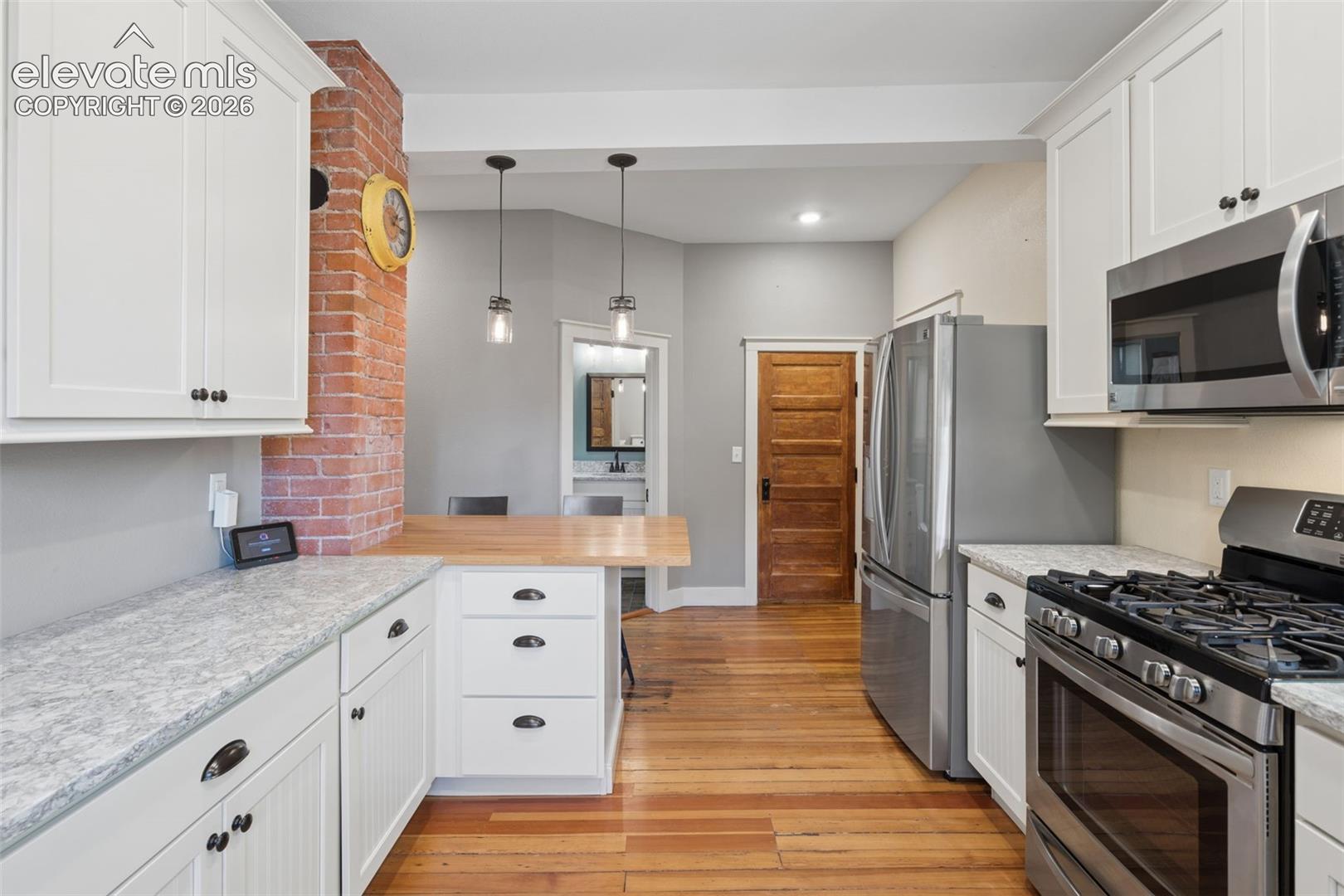 Kitchen featuring exposed brick accent, stainless appliances