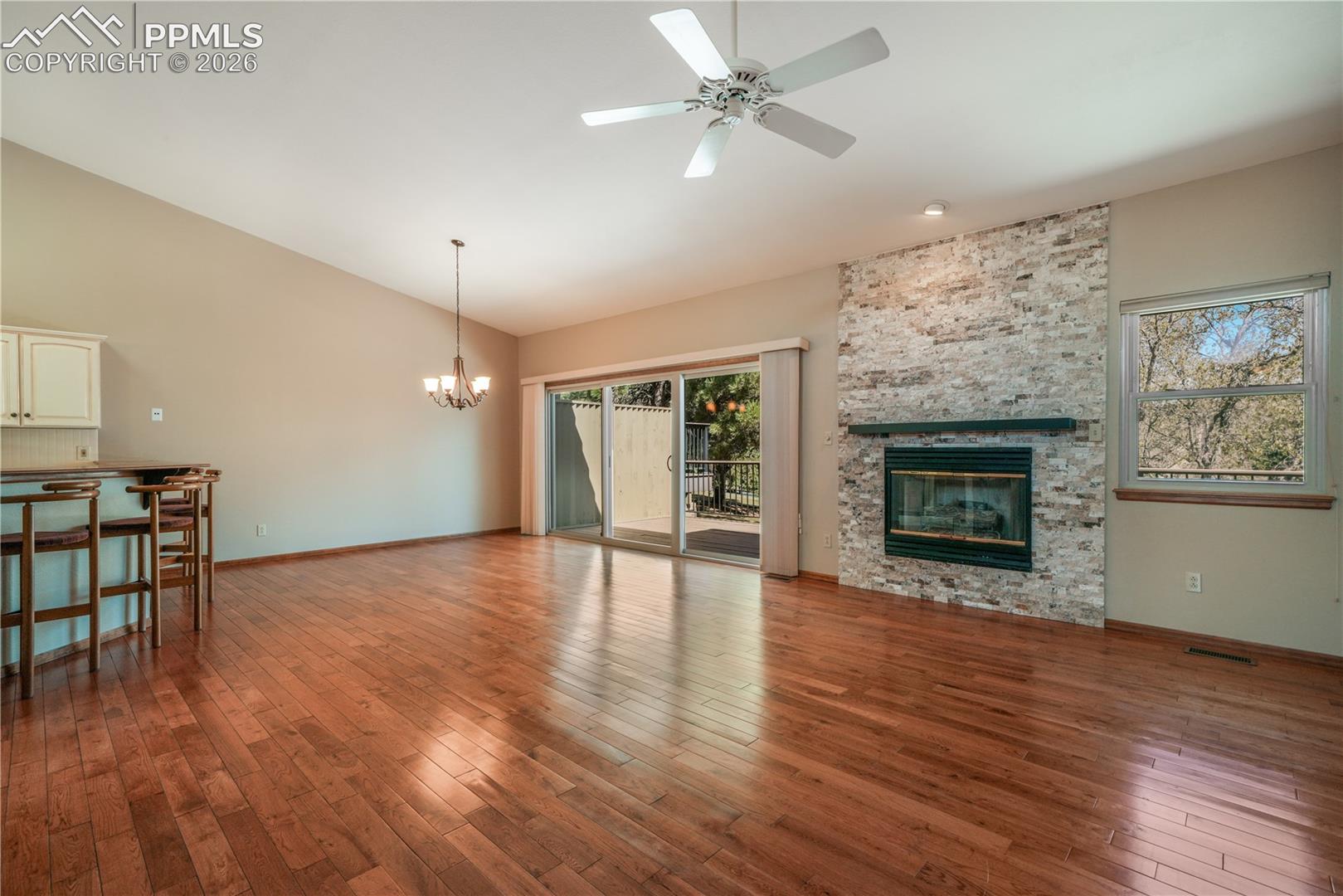 Main living room with hardwood floors, gas fireplace, extended patio doors to private deck