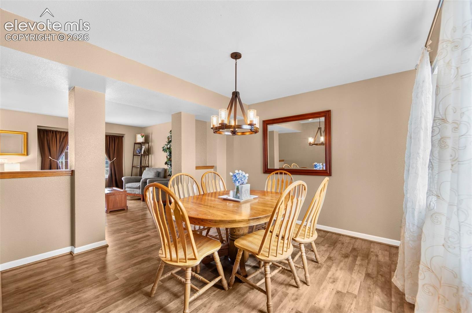 Dining area featuring wood-finish flooring, neutral wall tones, and an overhead chandelier with clear glass shades