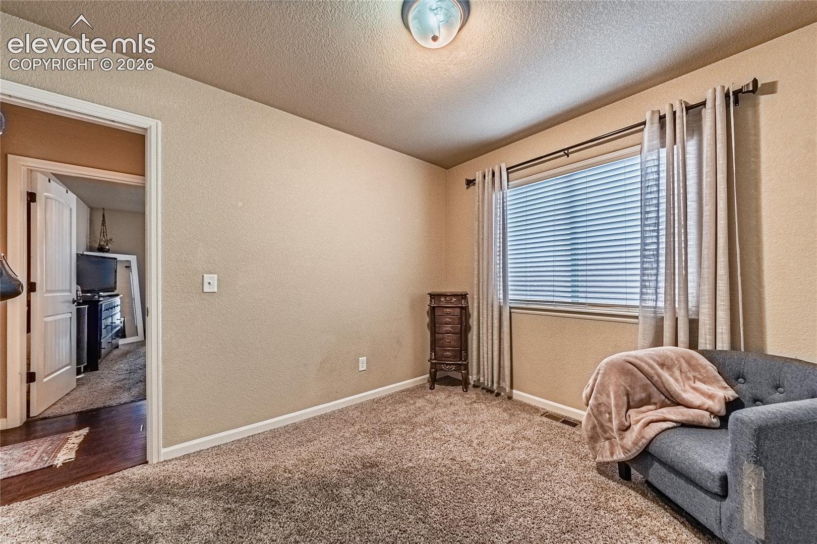 Bedroom featuring a textured wall, carpet floors, and a textured ceiling