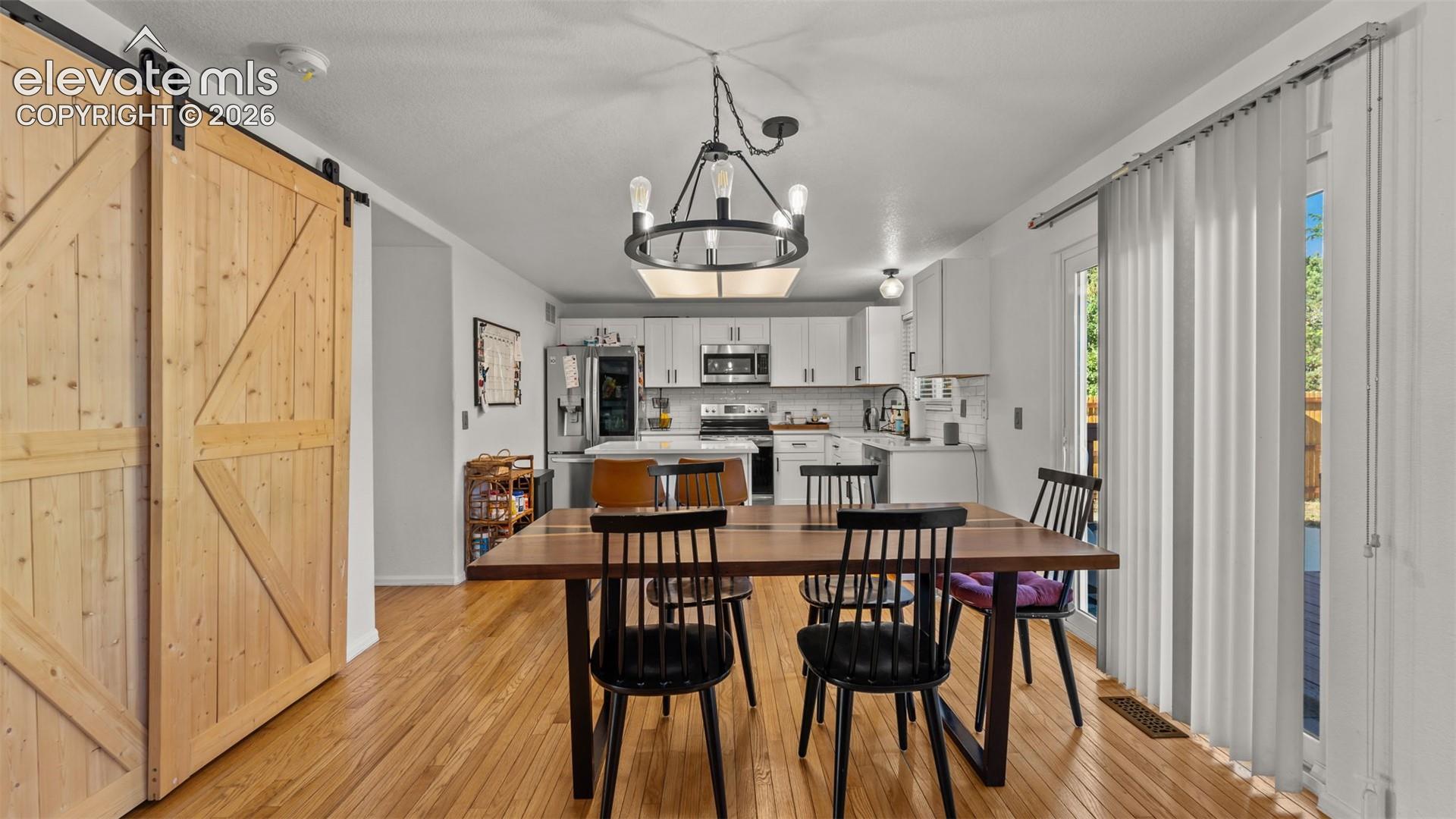 Wood-finish flooring throughout, with a large dining area featuring a modern chandelier
