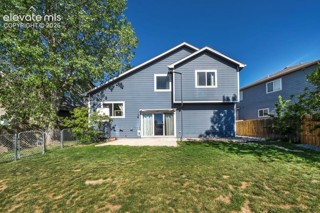 Rear exterior featuring horizontal lap siding, a concrete patio, sliding glass doors, and a fenced-in yard