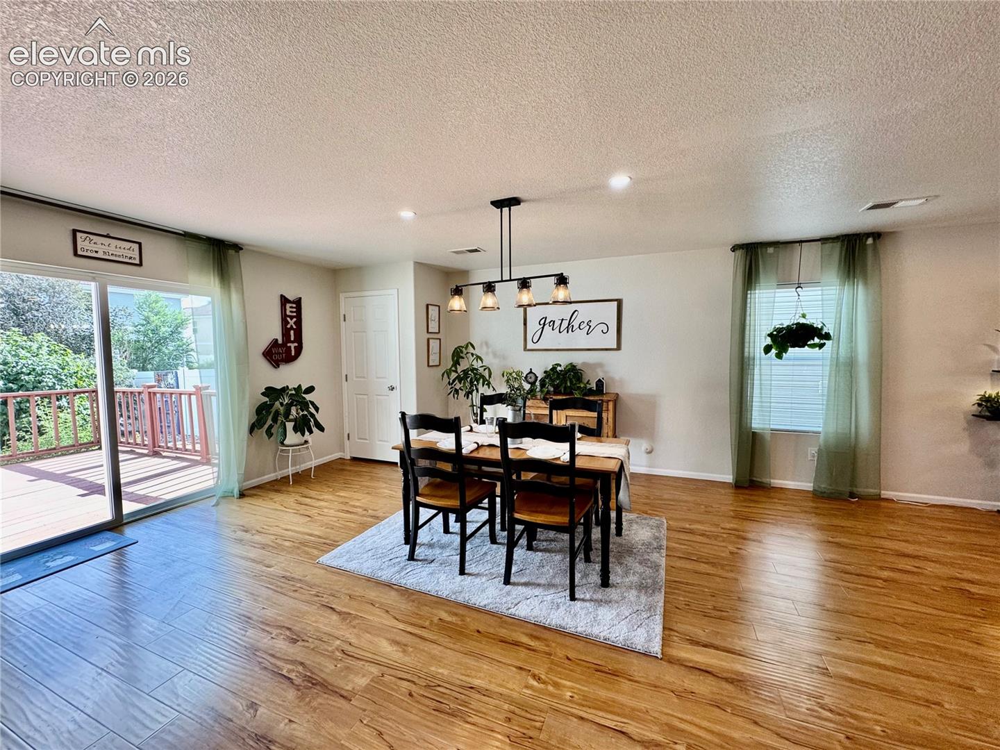 Open-concept dining area featuring wood-finish flooring, recessed lighting, and a sliding glass door providing direct access to an outdoor deck