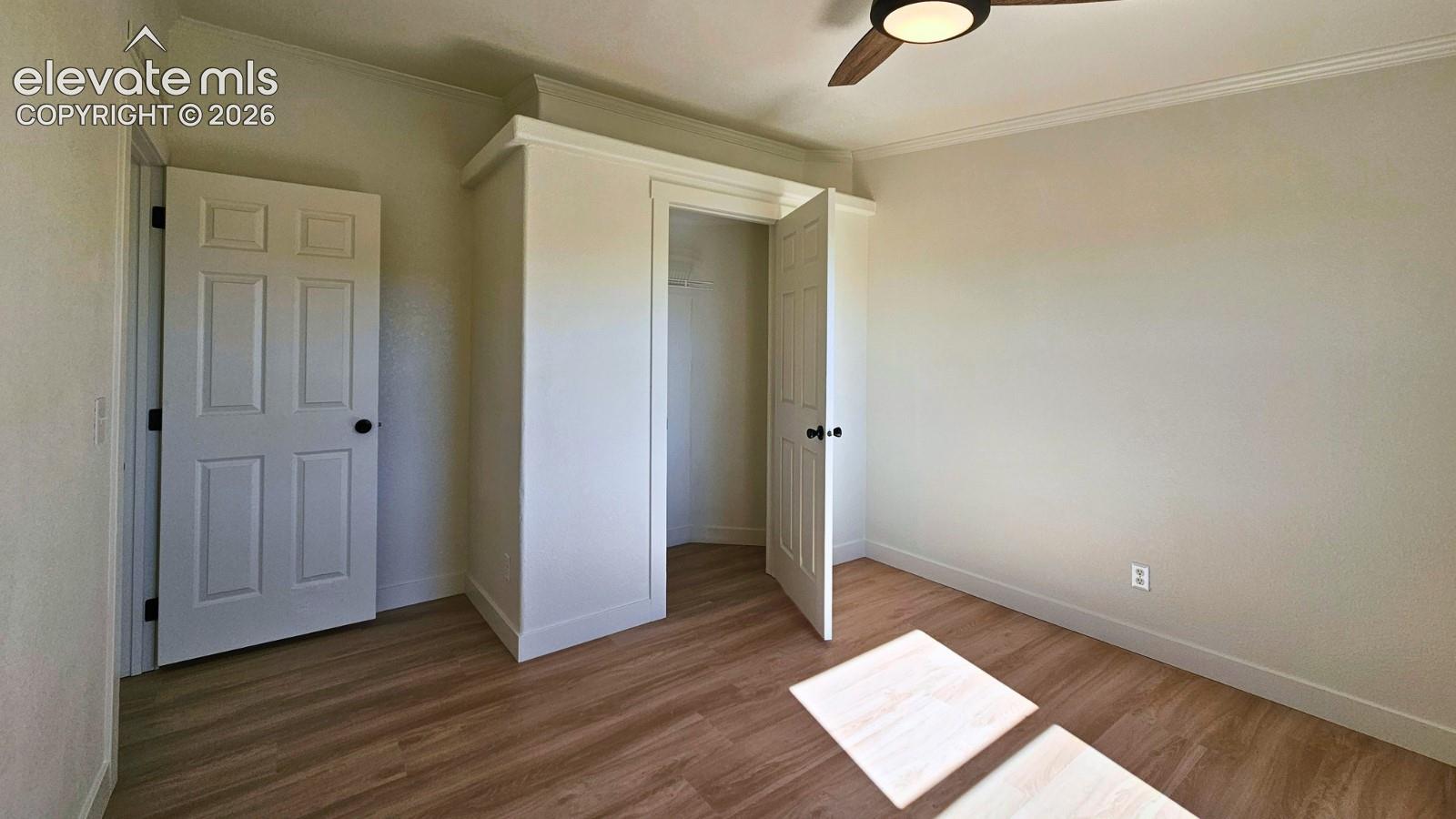 Room featuring wood-finish flooring, a ceiling fan with integrated lighting, and a built-in closet with paneled doors