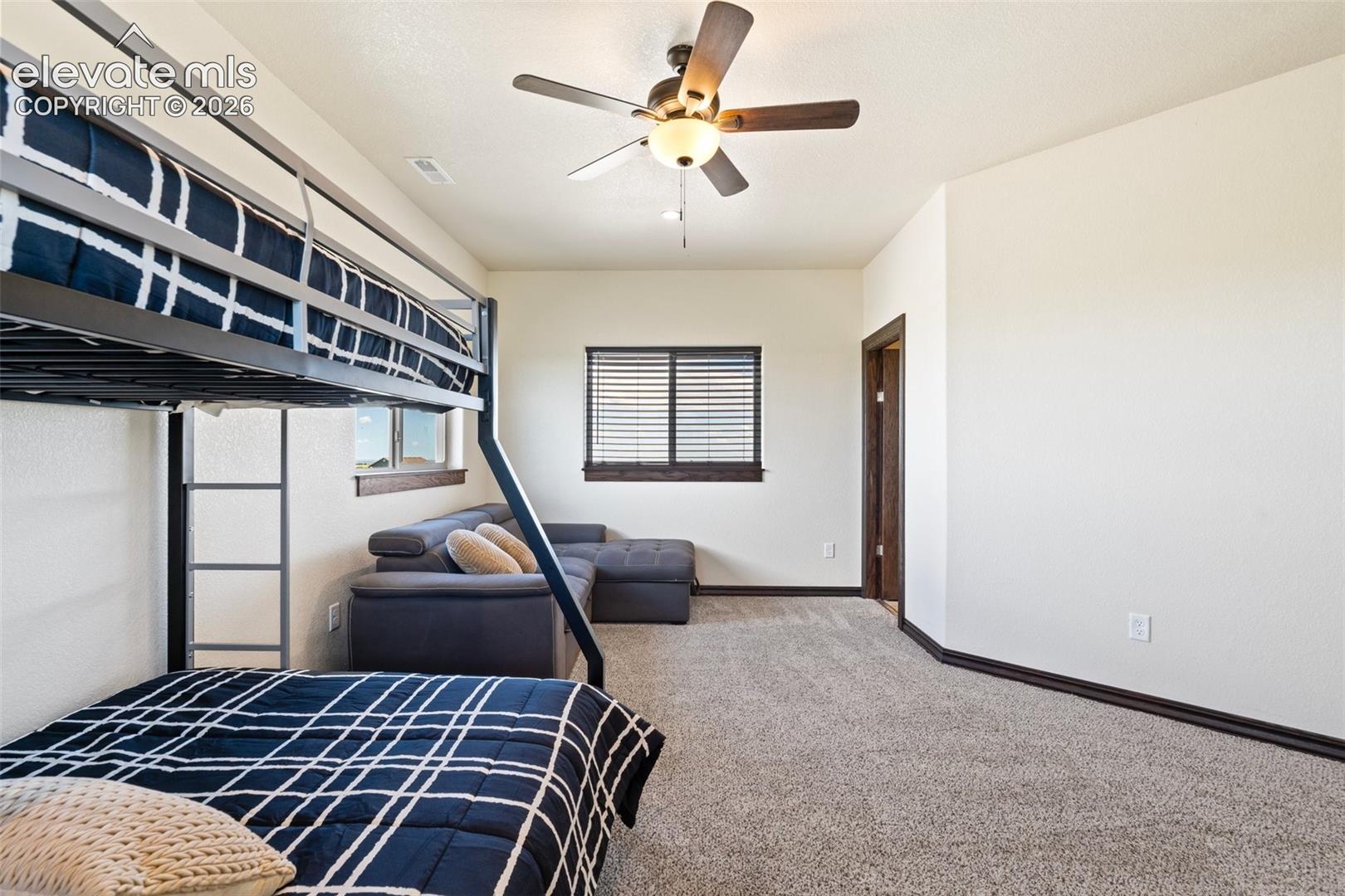Carpeted room featuring a ceiling fan with light fixture, a window with horizontal blinds, and a built-in doorframe with dark wood trim