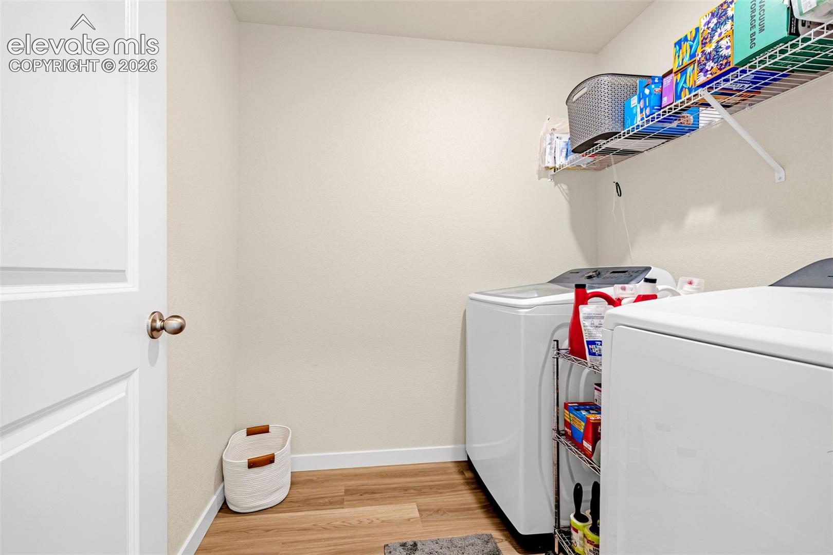 Dedicated laundry area featuring wood-finish flooring