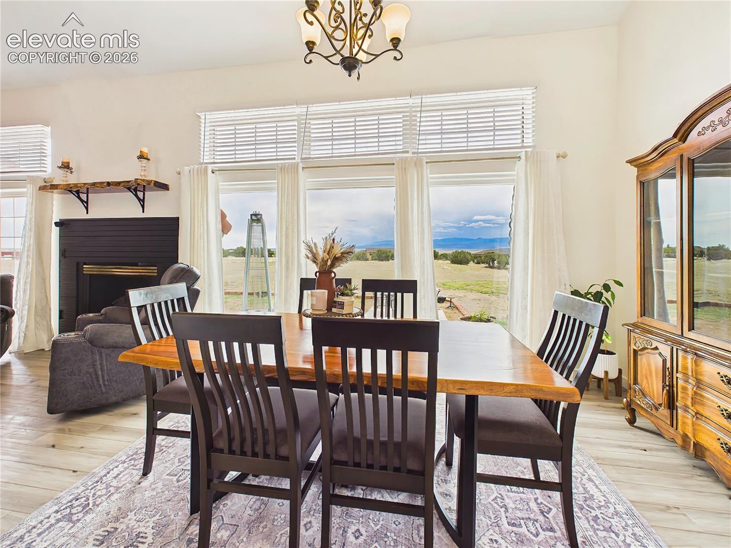 Spacious dining area is surrounded by oversized windows that fill the space with natural light and frame beautiful mountain and acreage views.