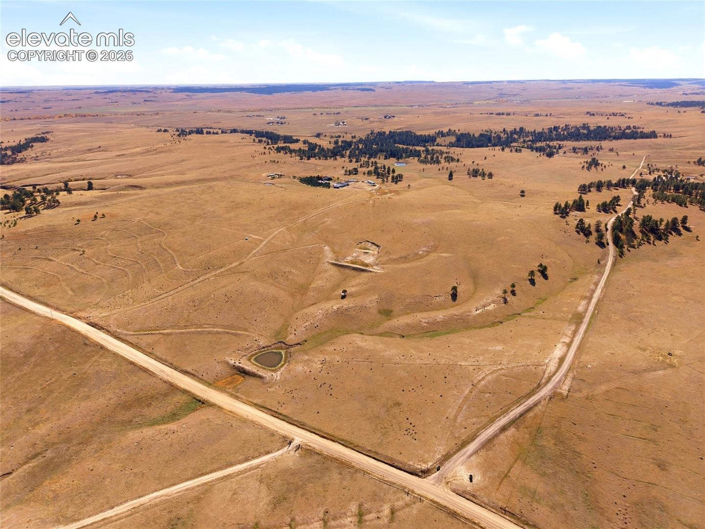 Expansive acreage featuring rolling topography, open meadows, clusters of native trees, and a natural pond