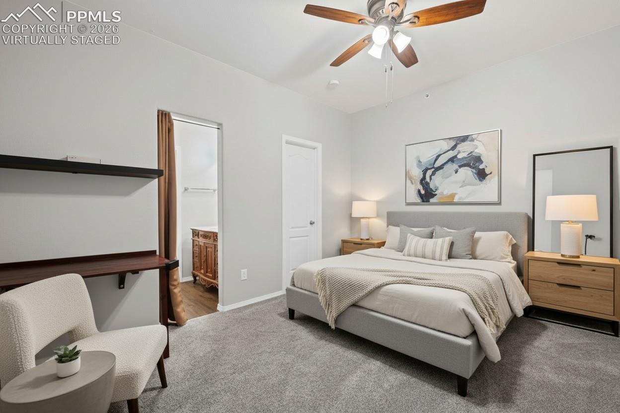 Bedroom with en-suite bathroom.  carpet, baseboards, custom window treatments and a ceiling fan. This photo is virtually staged.