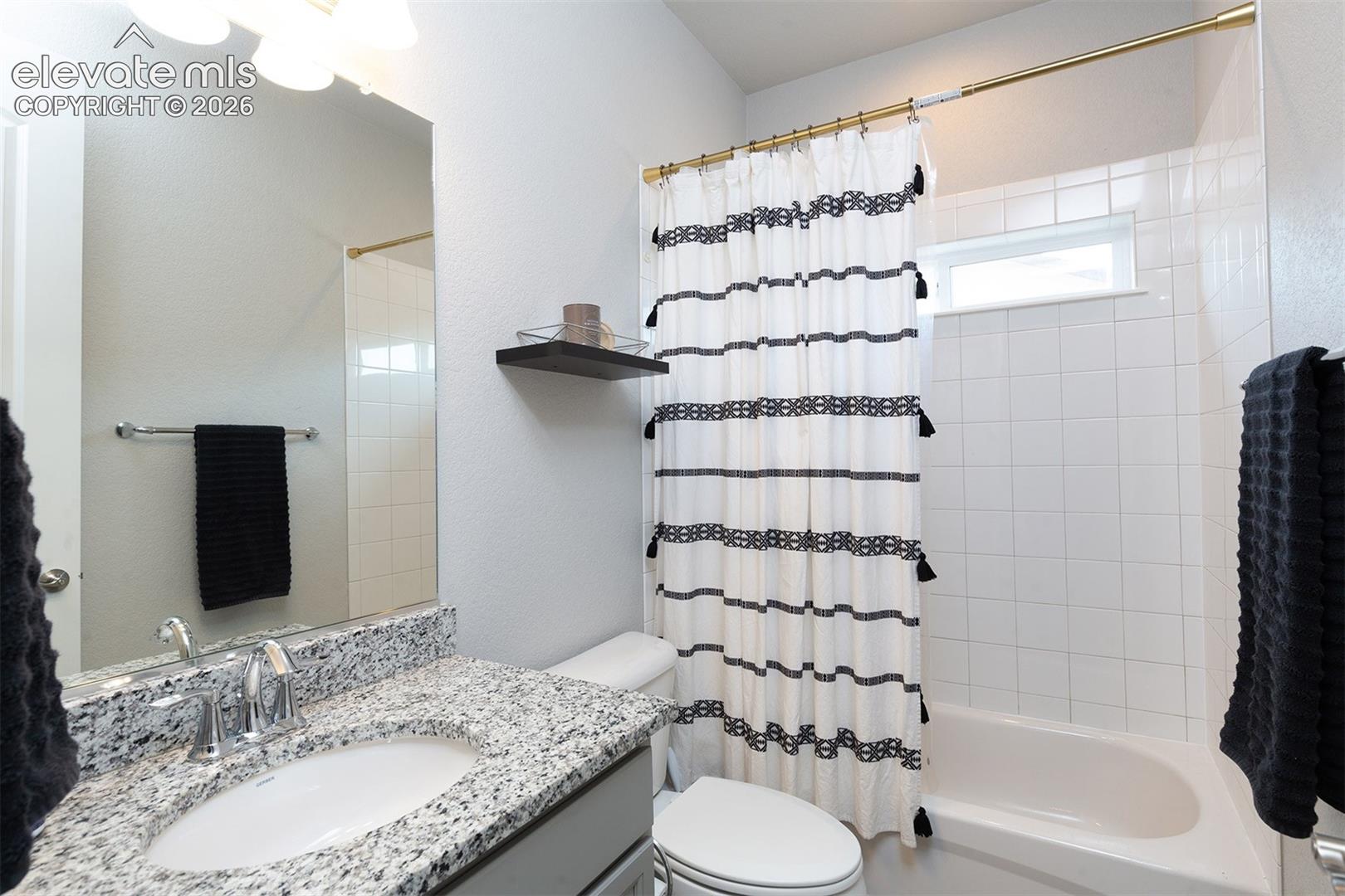 Front Bathroom - Vanity with granite-style countertop, single basin sink, and chrome faucet