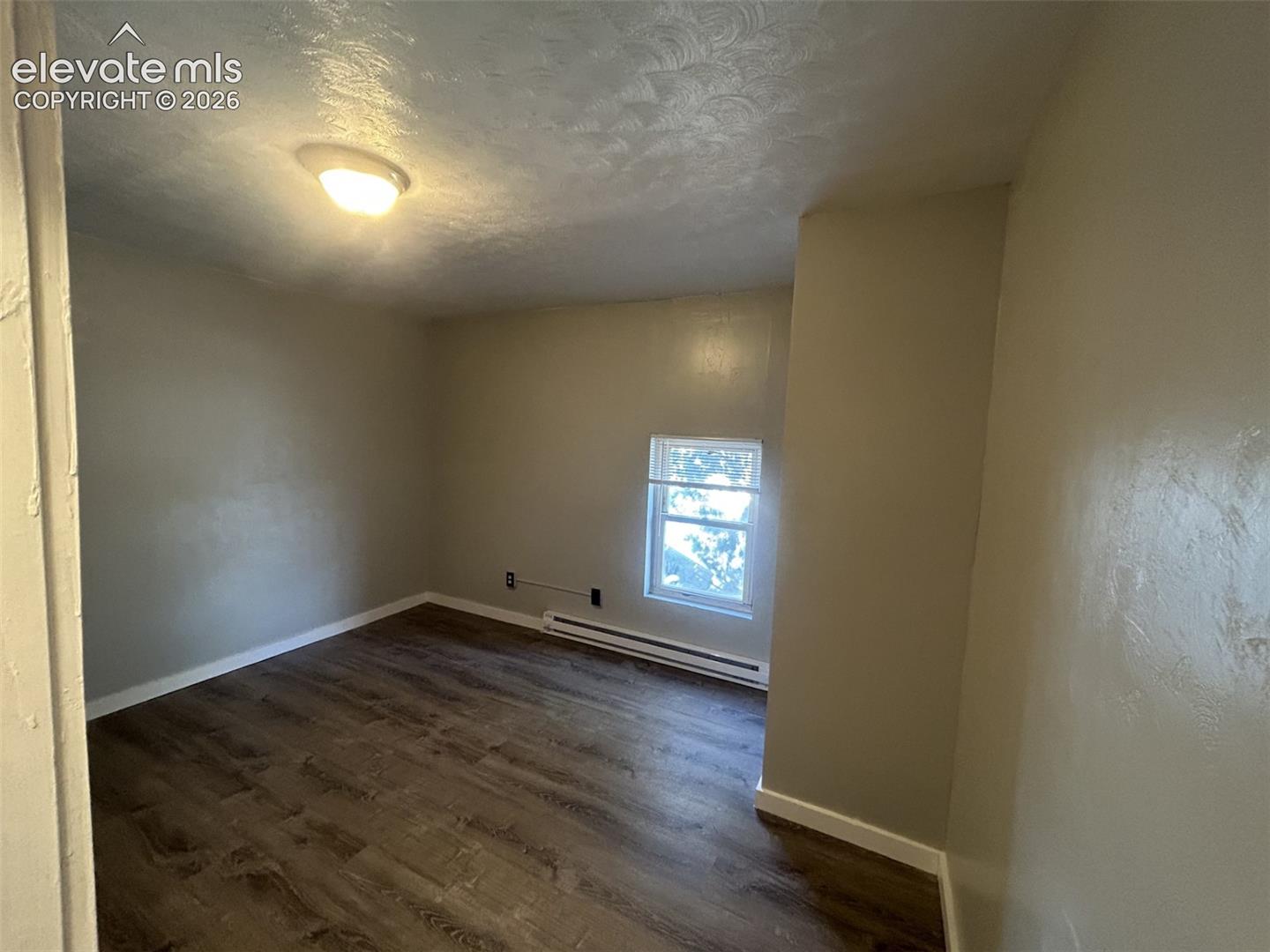 Neutral wall finishes, wood-finish flooring, a window providing natural illumination, and a flush-mount ceiling light fixture