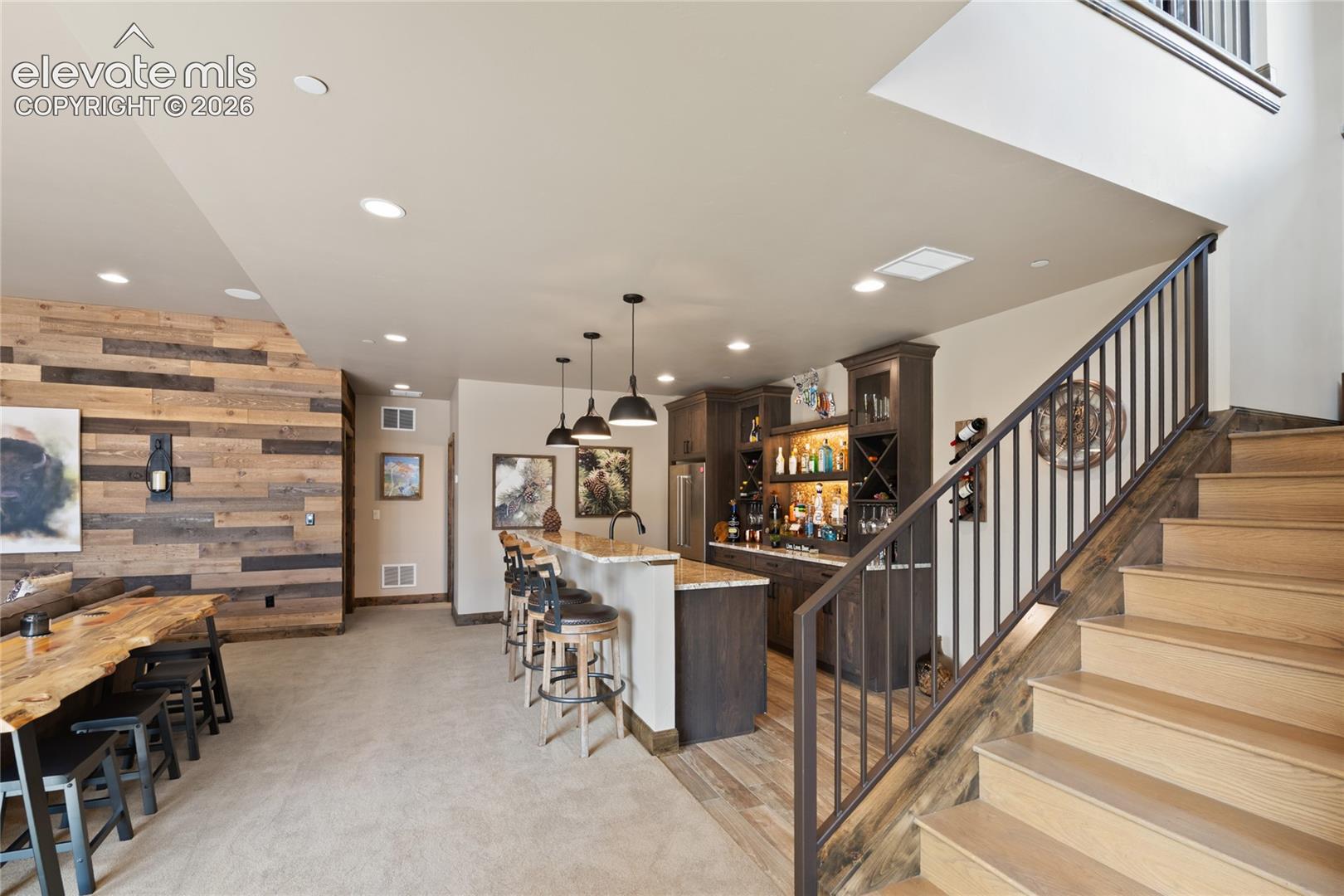 The party officially has a destination. Lower-level entertaining space with full wet bar, granite seating island, custom wood accent wall, and room to host the whole crew.
