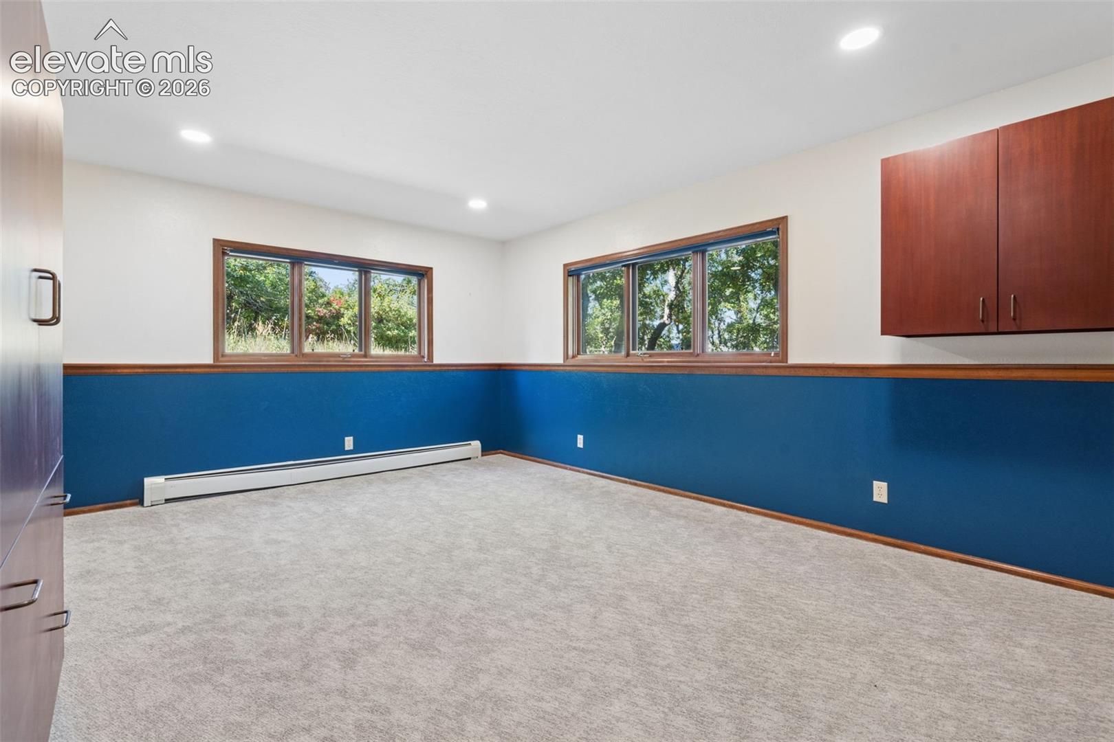 Recessed lighting, wood-trimmed windows, wall-mounted cabinetry, built-in baseboard heating, and carpeting