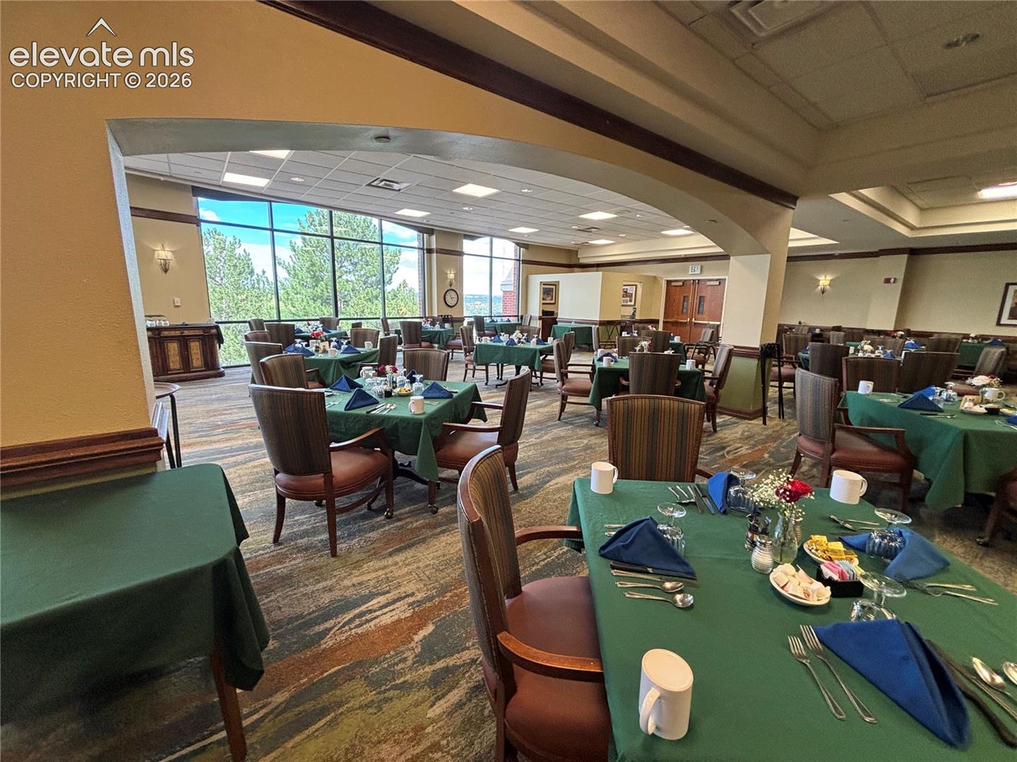 Expansive dining area with large windows, patterned carpeting, and recessed lighting