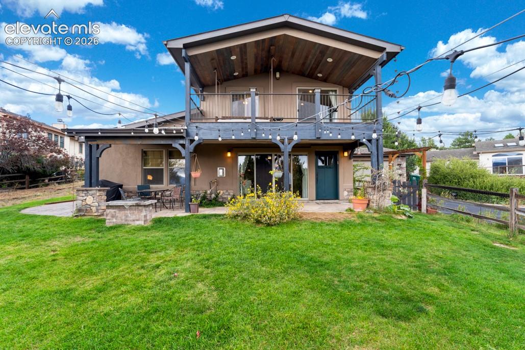 Two-story exterior with a ground-level patio featuring a built-in stone fire pit, a covered outdoor living area, and a second-story balcony