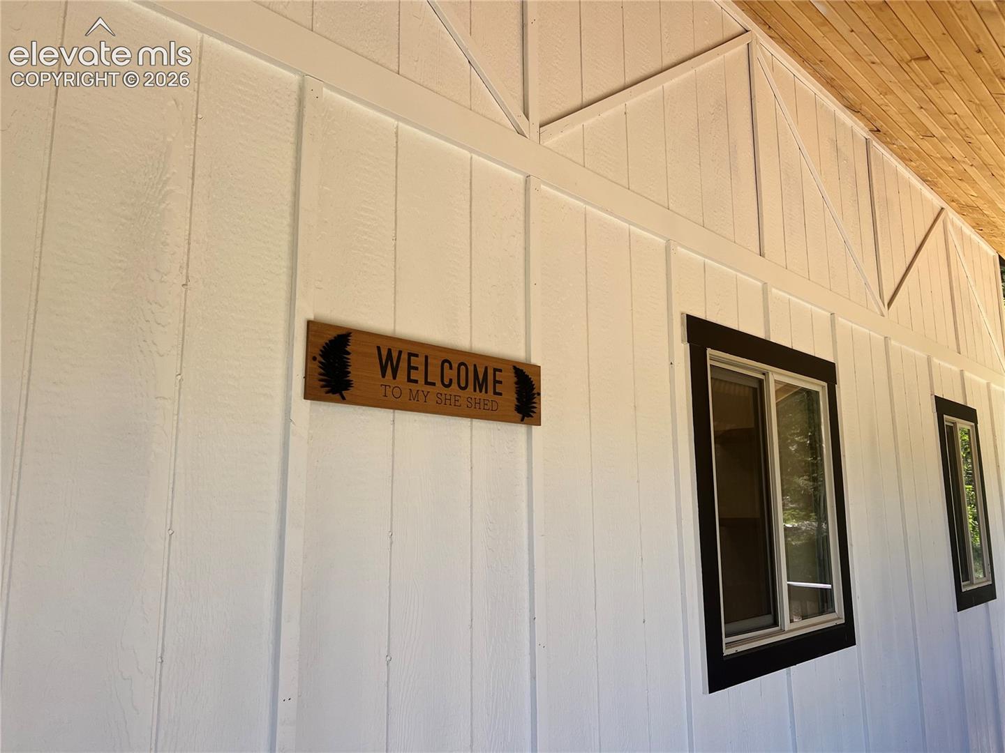 White board and batten siding, dark-trimmed windows, and wood-finish soffit