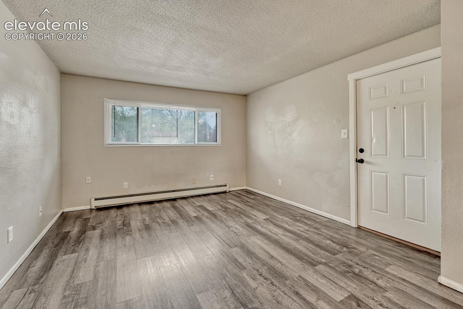 Wood-finish flooring, white paneled door, and a horizontal window frame