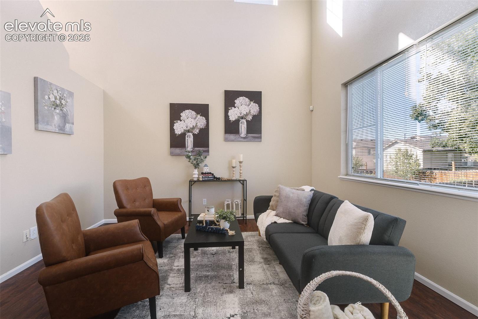 High ceilings featuring expansive wall space, complemented by wide windows and wood-finish flooring