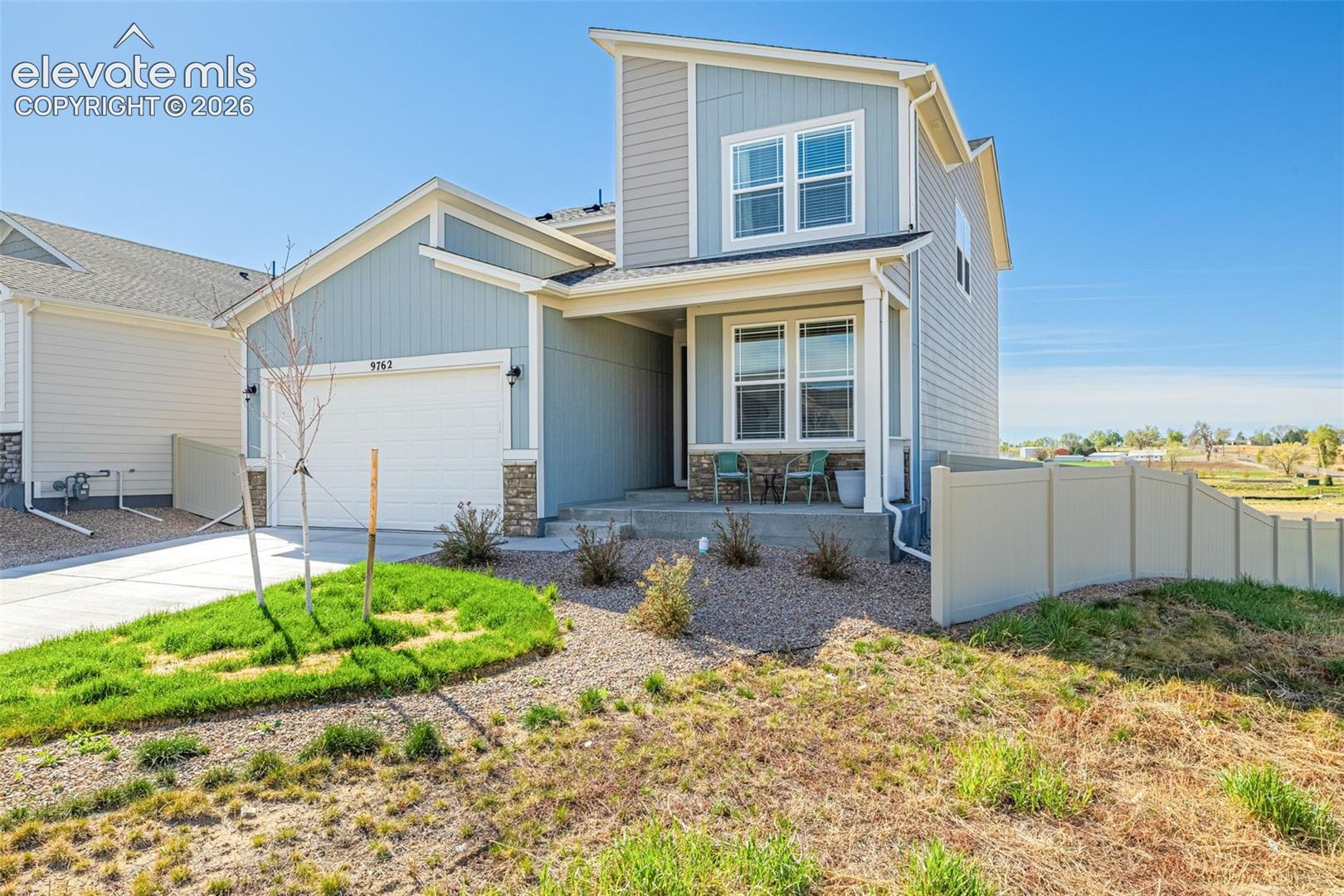 Contemporary exterior featuring light blue siding, stone veneer accents, an attached garage, and a covered front porch