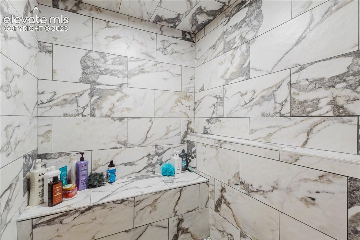 Shower enclosure featuring large format white and gray variegated tiles