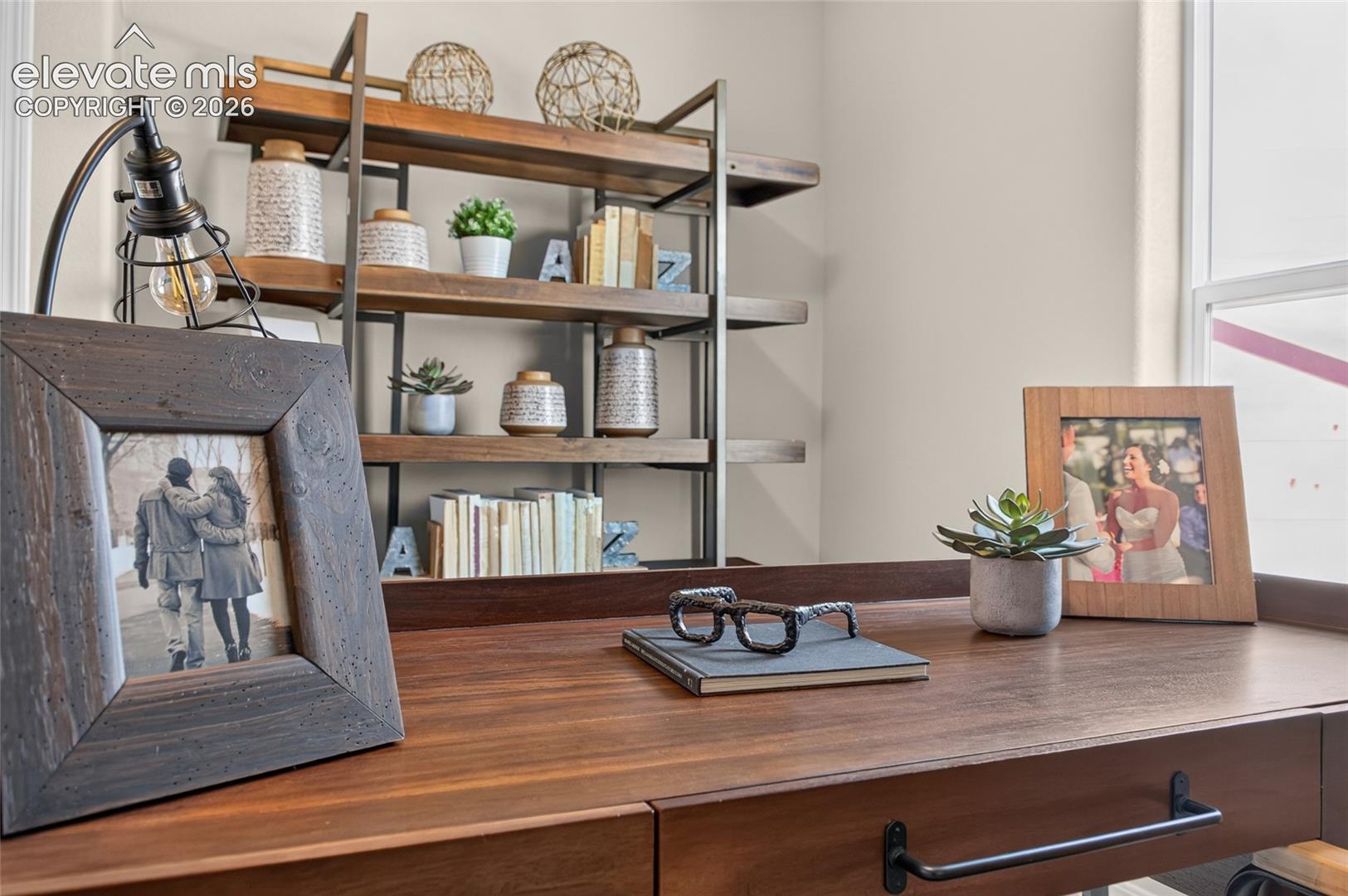 Built-in wood-finish desk featuring a drawer with matte black hardware and an integrated metal-framed shelving unit with wooden tiers